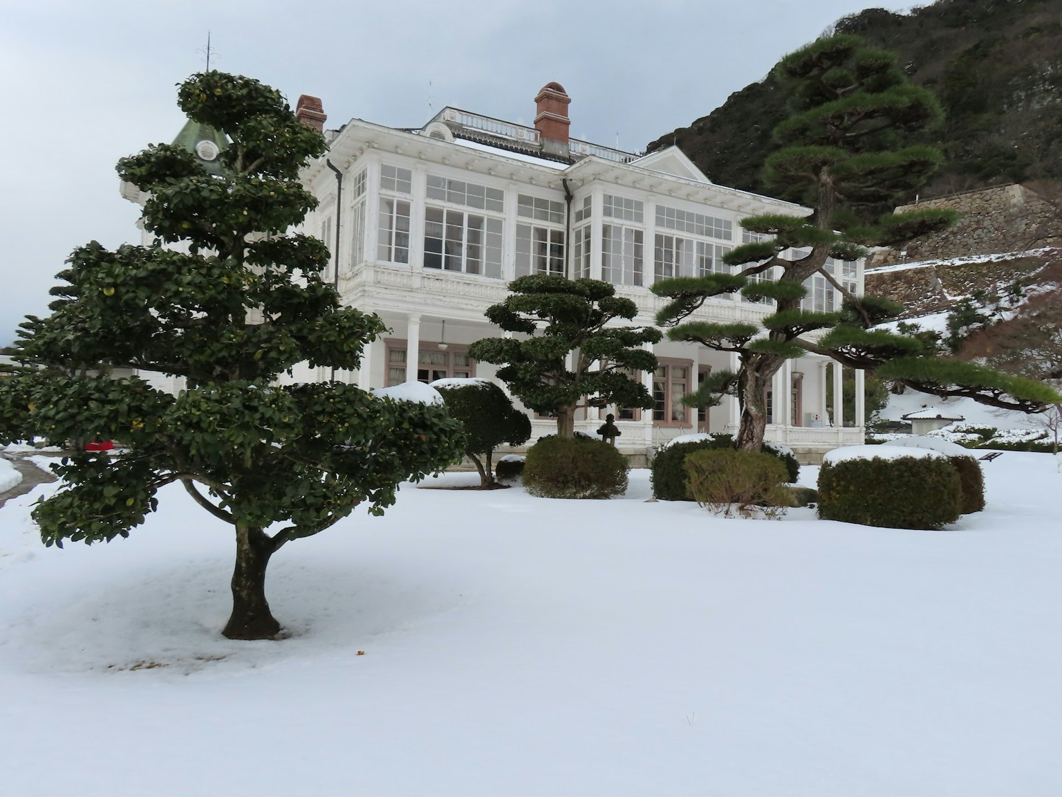 Magnifique manoir blanc couvert de neige avec des arbres de jardin bien entretenus