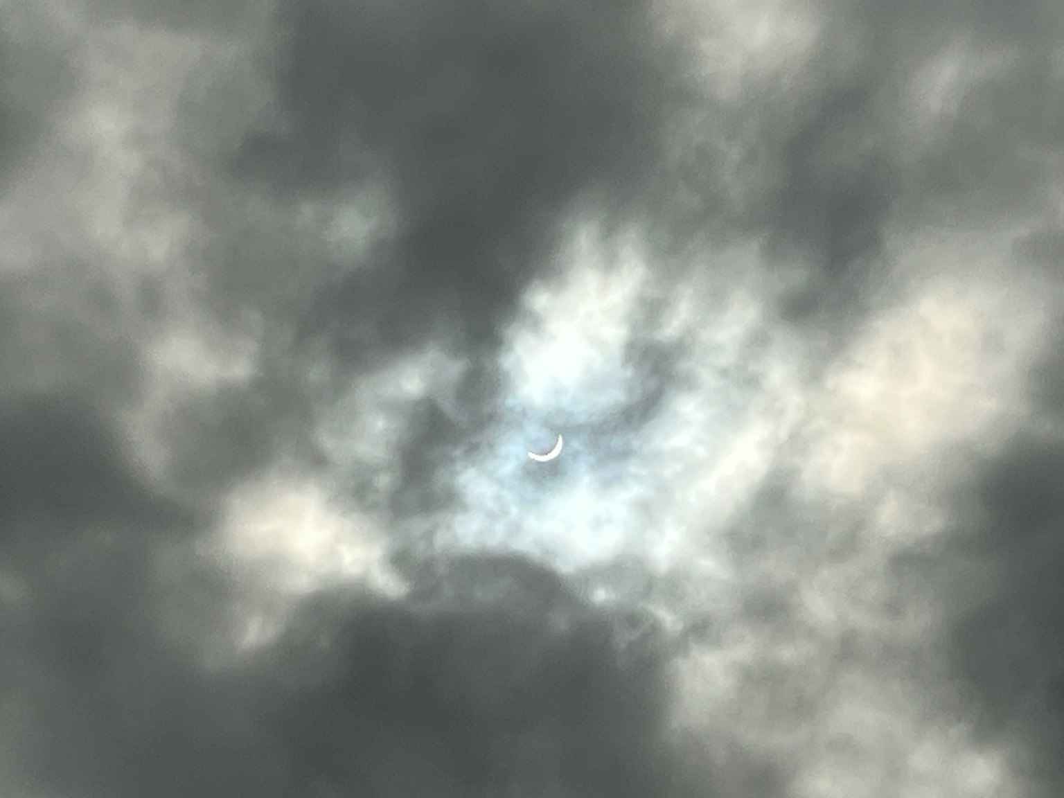 Un mince croissant de lune visible à travers un ciel nuageux