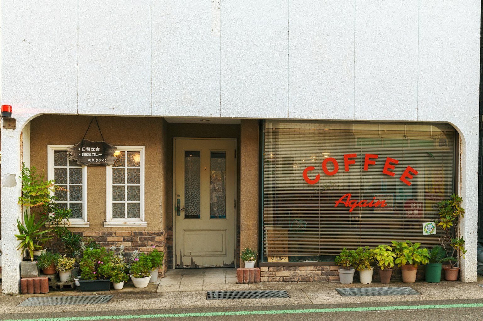 ด้านนอกของร้านกาแฟที่มีพืชสีเขียวเรียงรายอยู่ที่ทางเข้า