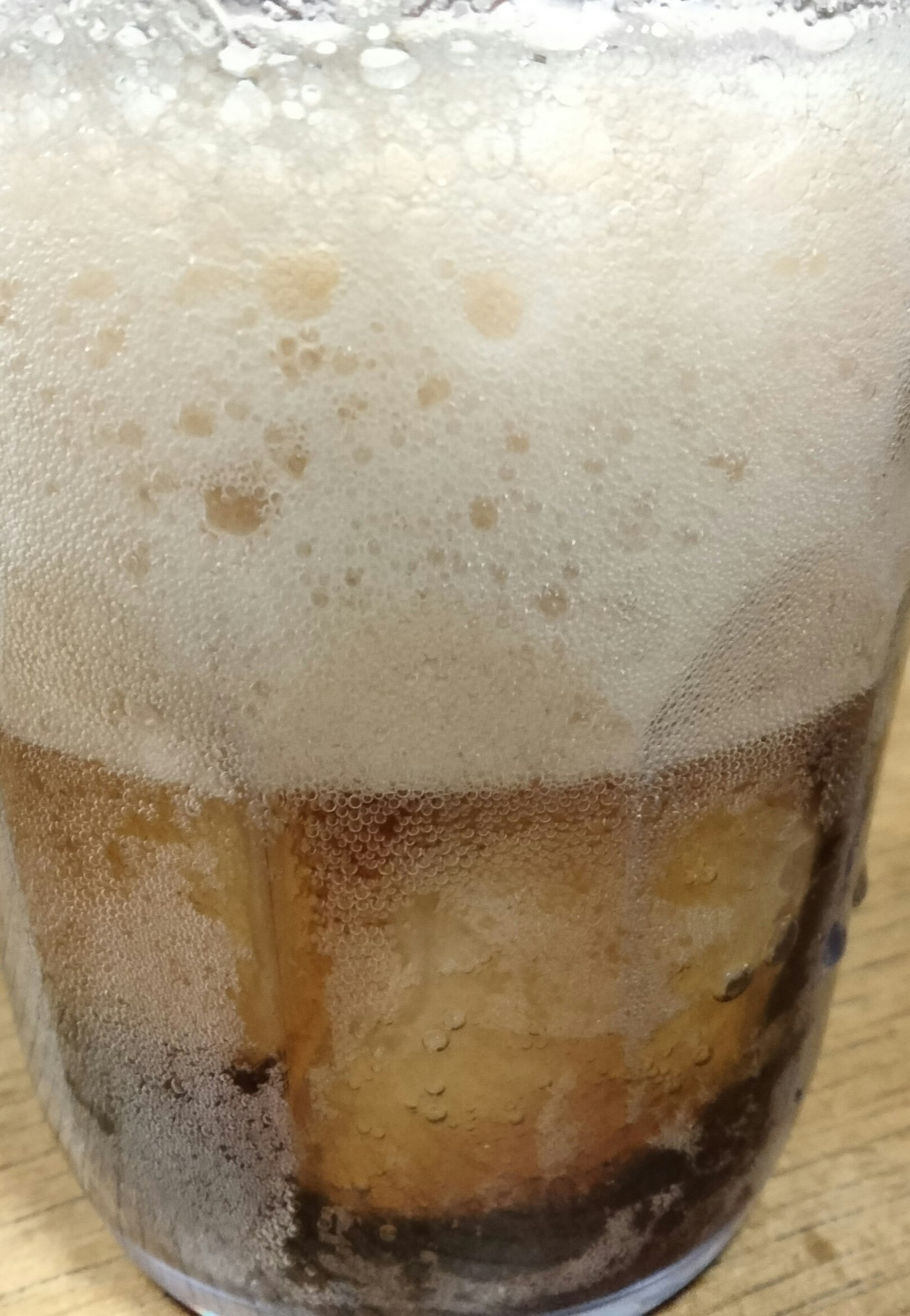 泡立った飲み物と氷が入ったグラス