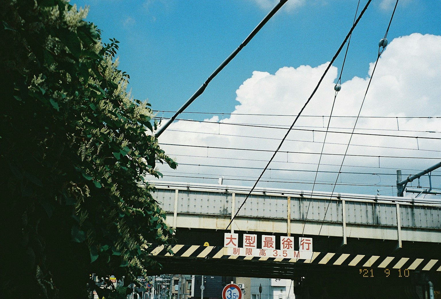 Blick auf eine Eisenbahnüberführung mit elektrischen Leitungen unter einem blauen Himmel