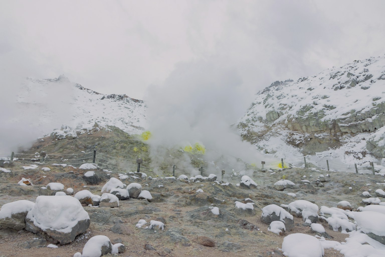Snow-covered mountains with geothermal steam and rocks