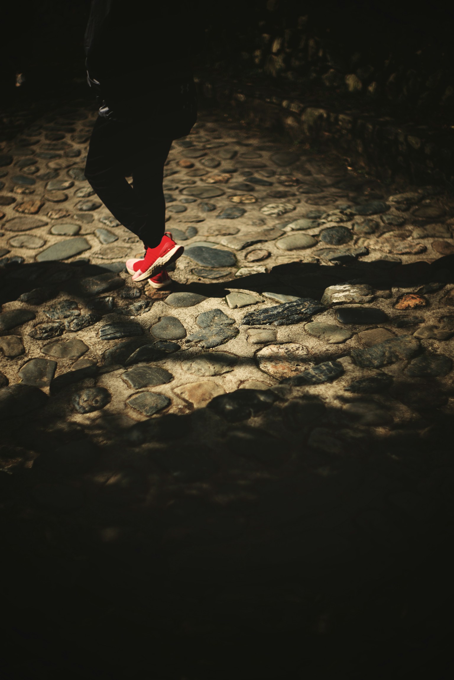 Orang yang berjalan di jalan berbatu dengan sepatu merah
