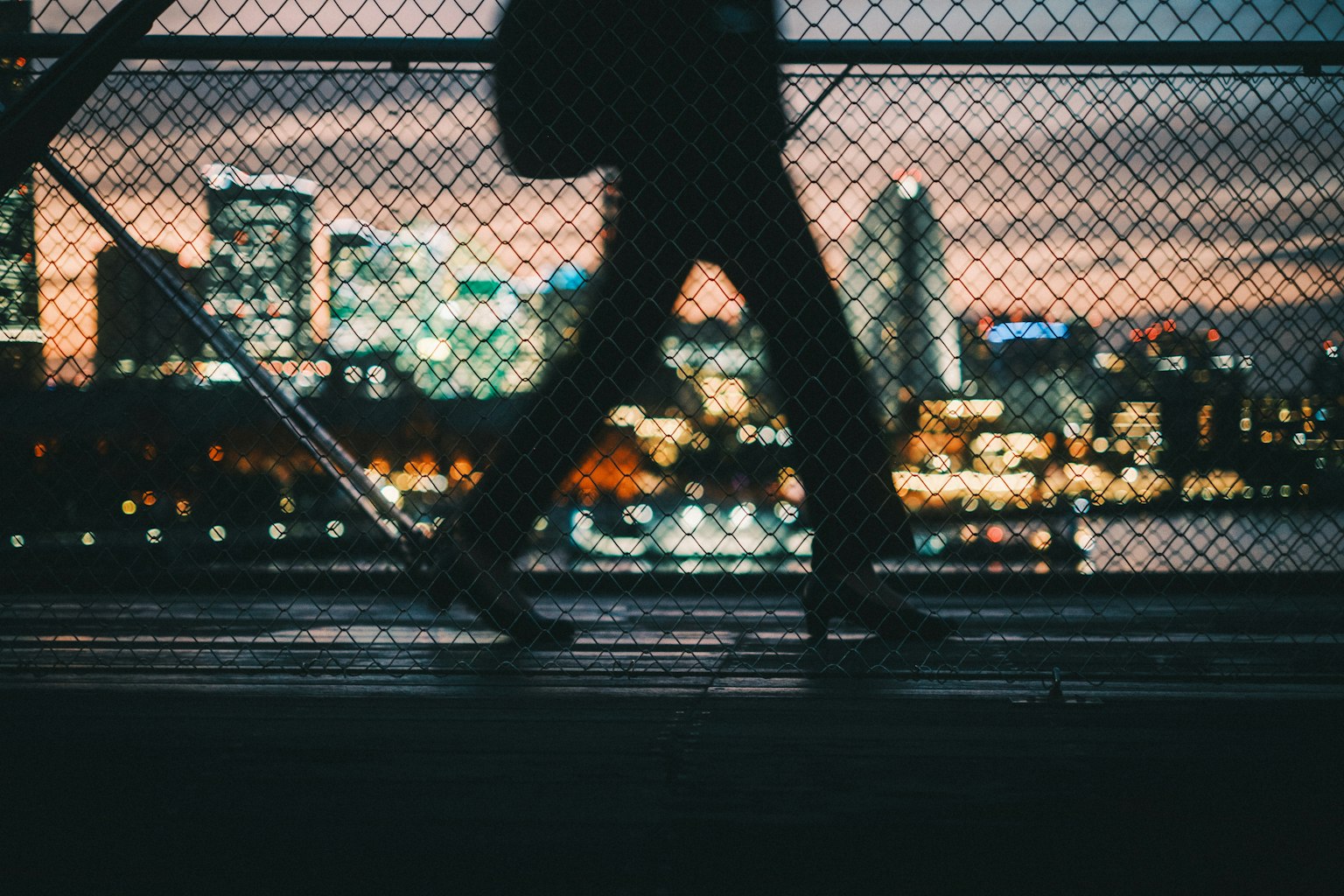 Silhouette einer Person, die gegen eine Stadtlandschaft bei Dämmerung geht