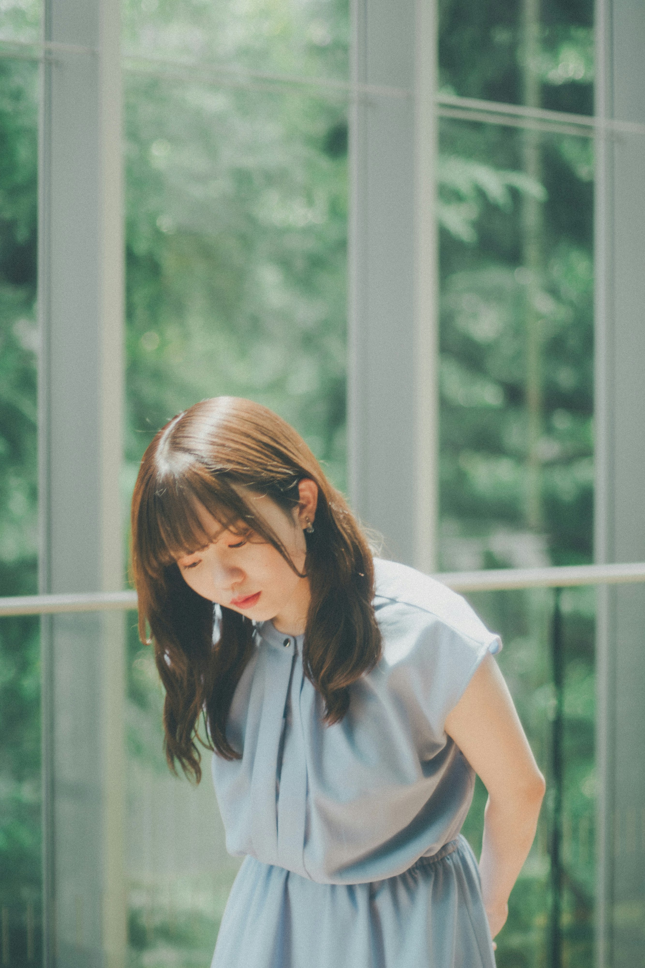 透過玻璃可見綠意的女性肖像