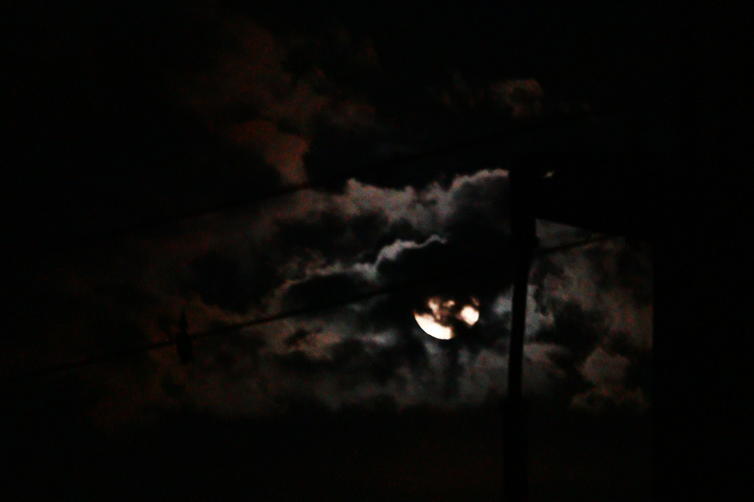 Lune partiellement cachée par des nuages dans un ciel sombre