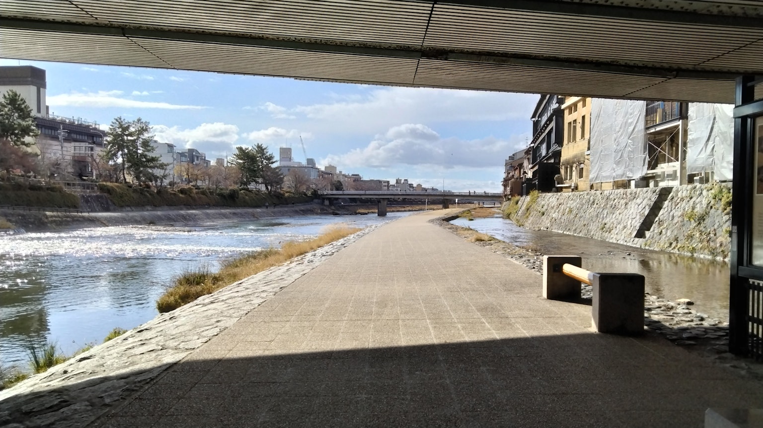 Vista panoramica di un sentiero lungo il fiume sotto un ponte Luce naturale e cielo blu