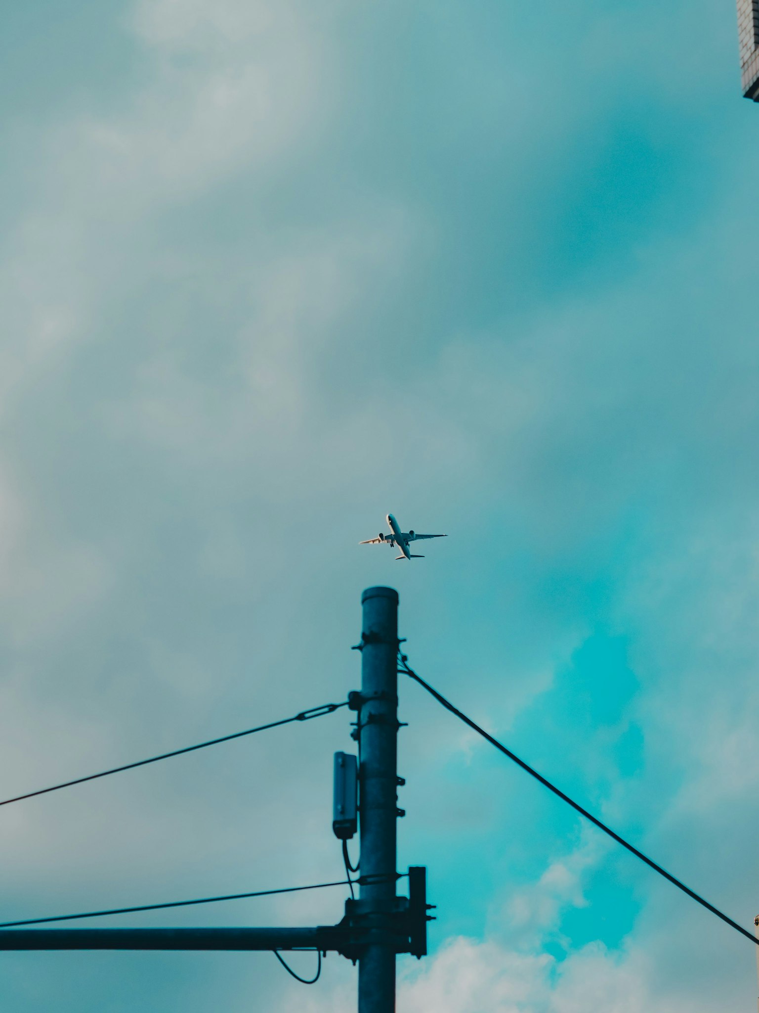 Image d'un avion volant dans le ciel bleu au-dessus d'un poteau électrique