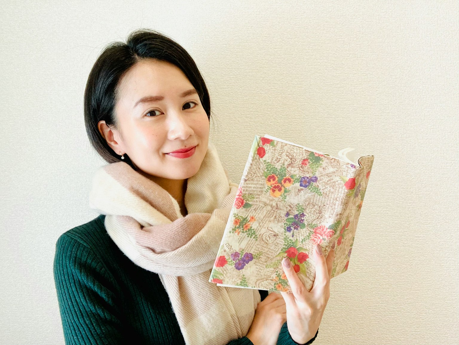 Frau lächelt, während sie ein blumengemustertes Buch hält