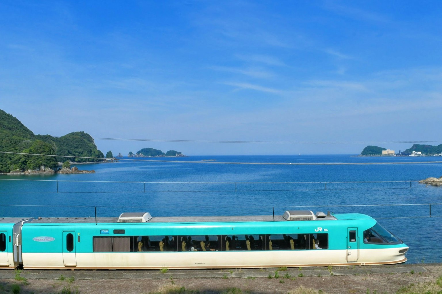 Tren detenido junto al mar azul bajo un cielo despejado