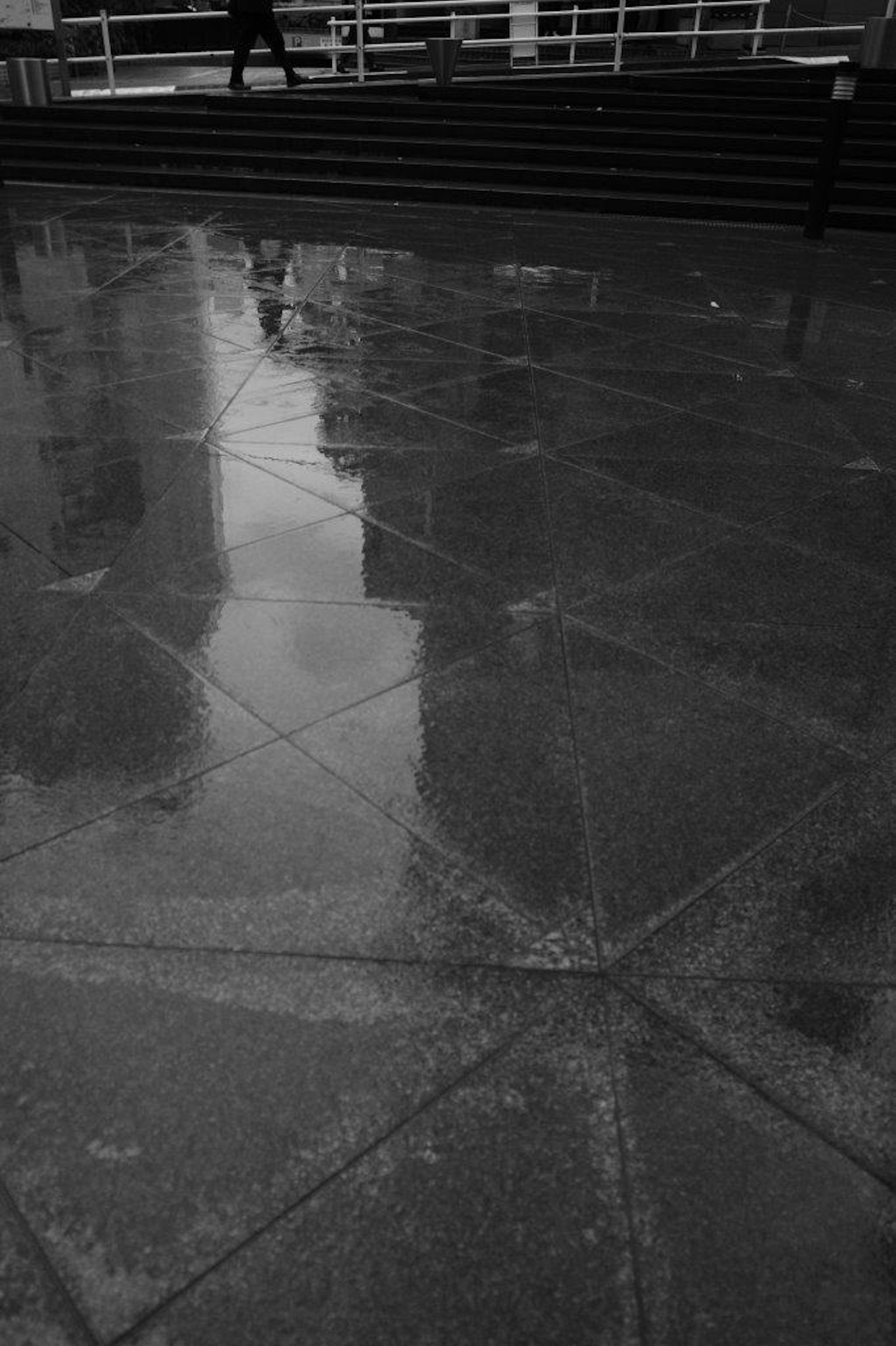 Monochrome Szene mit Reflexionen auf einem nassen Gehweg