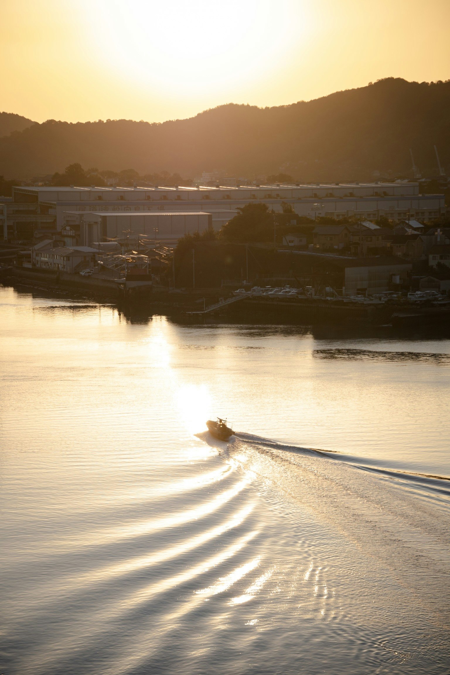 A small boat creating ripples on a river at sunset