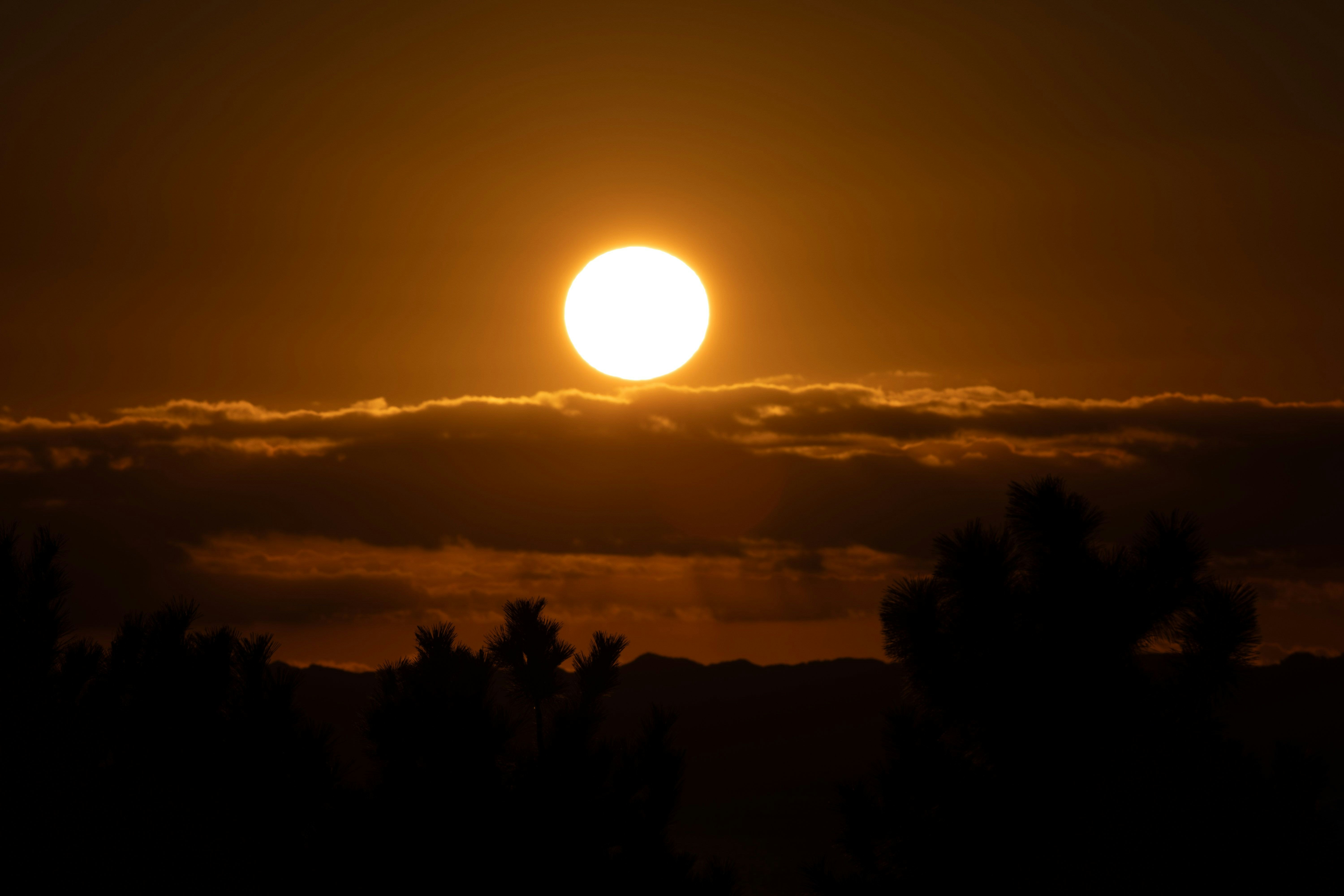 夕焼けの雲間から昇る太陽のシルエット