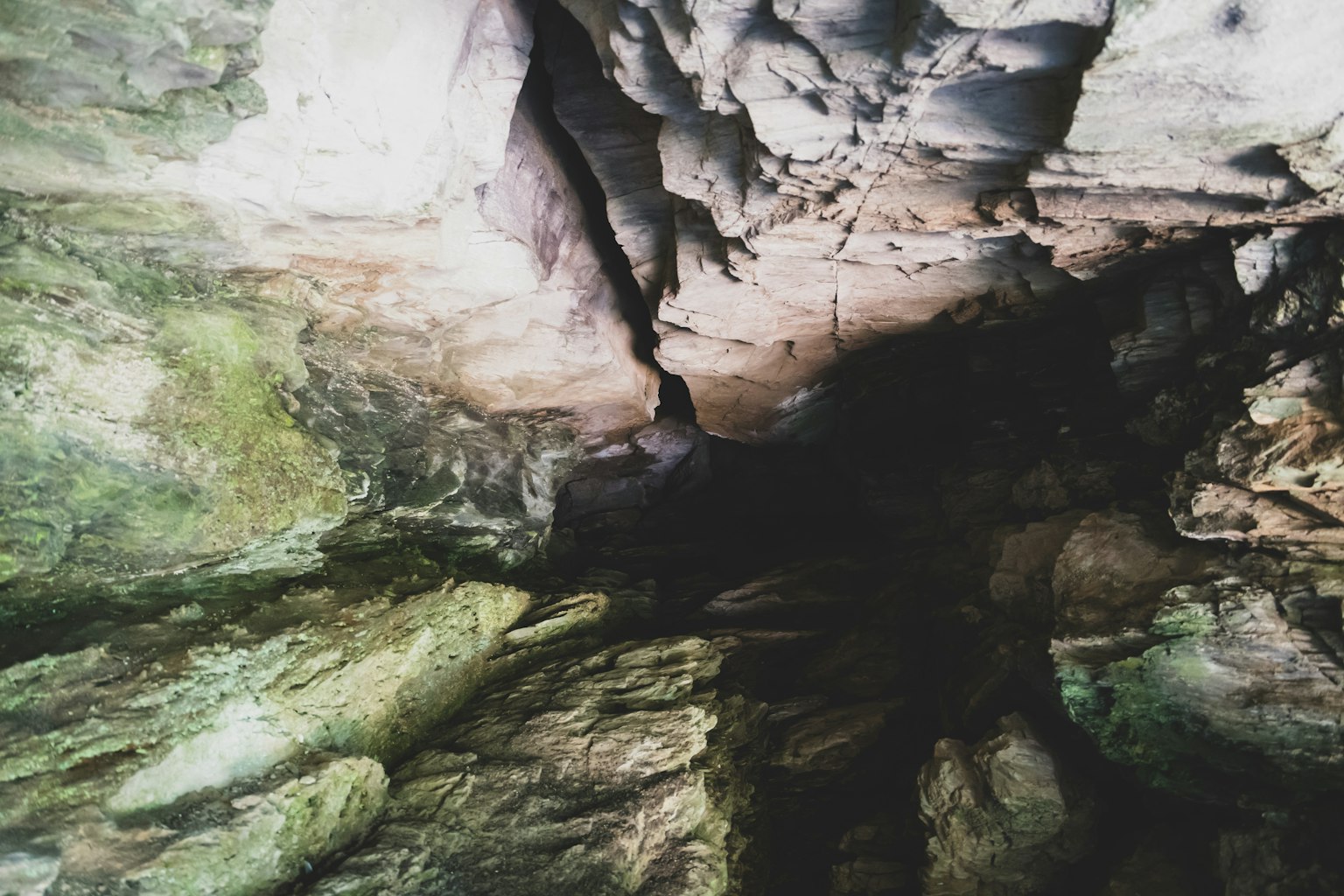 Close-up of cave ceiling showcasing natural rock textures and colors featuring green and gray hues
