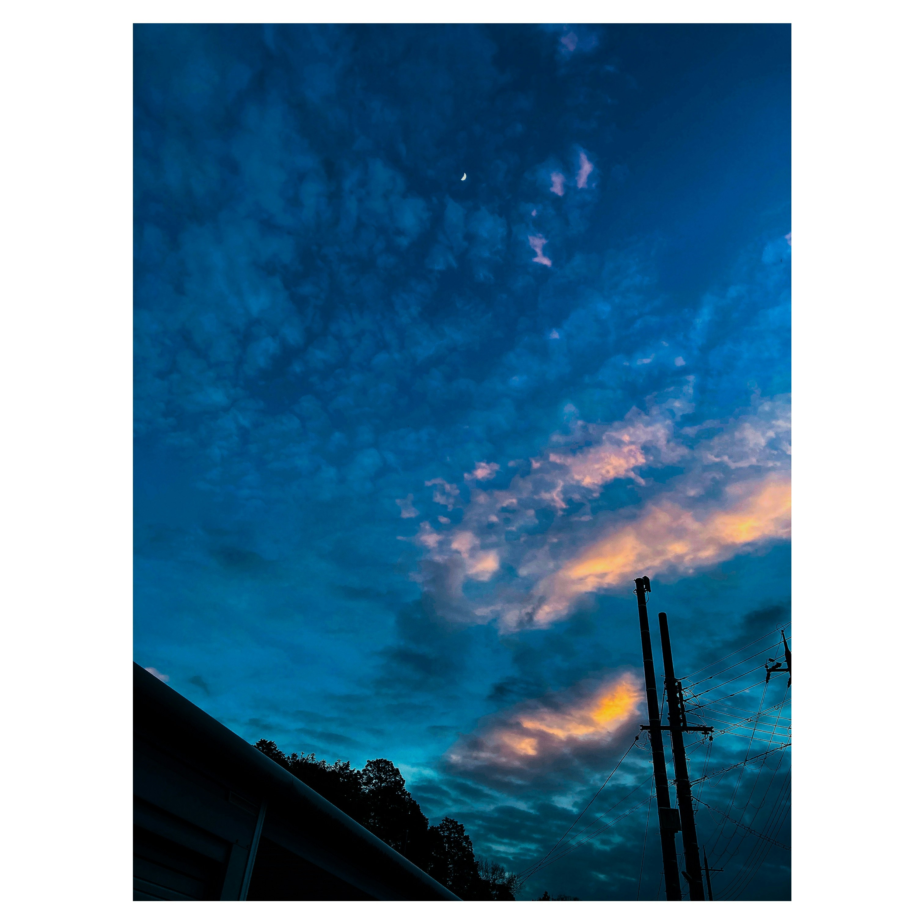 夕暮れの青い空に雲と電柱が立つ風景