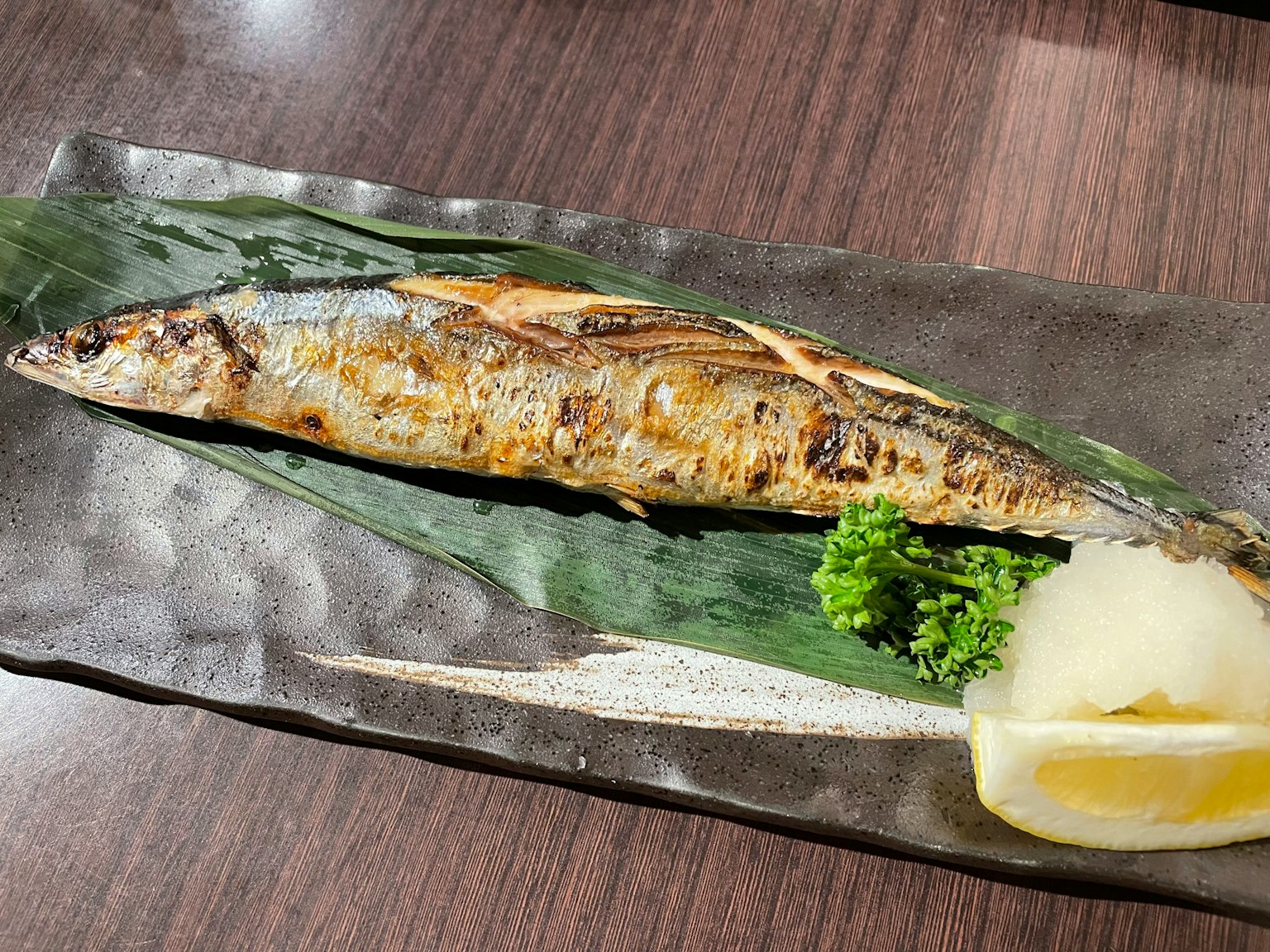 Trình bày cá nướng với sanma trang trí chanh và củ cải trắng