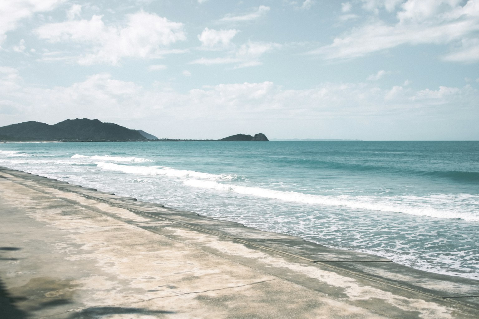 Pemandangan pantai yang tenang dengan laut tenang dan langit biru