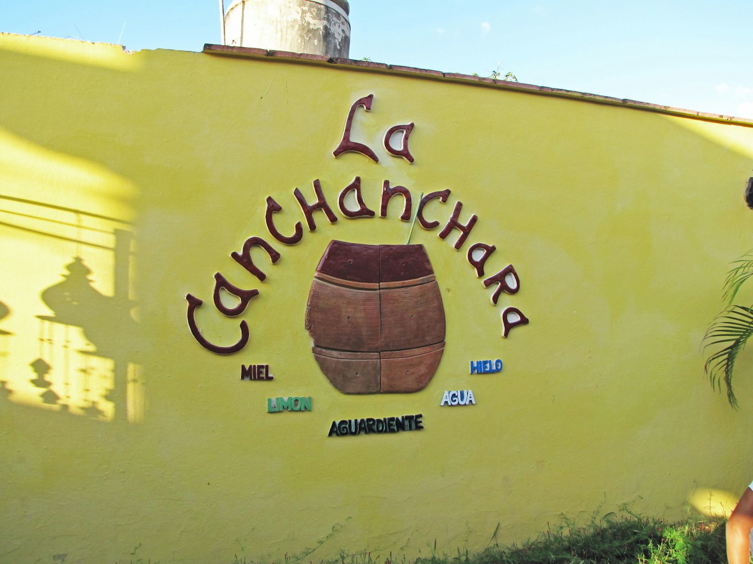 Buntes Schild von La Canchanchara an einer gelben Wand
