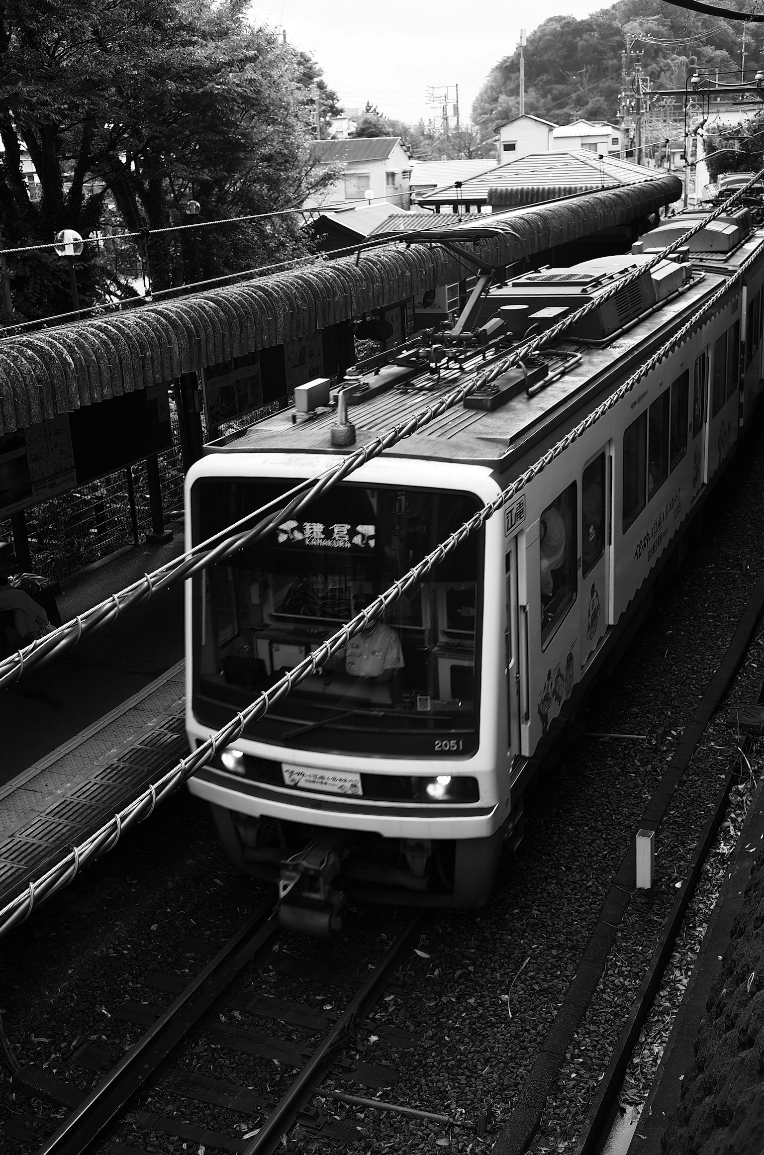 Gambar hitam putih kereta di rel dengan stasiun atap terlihat