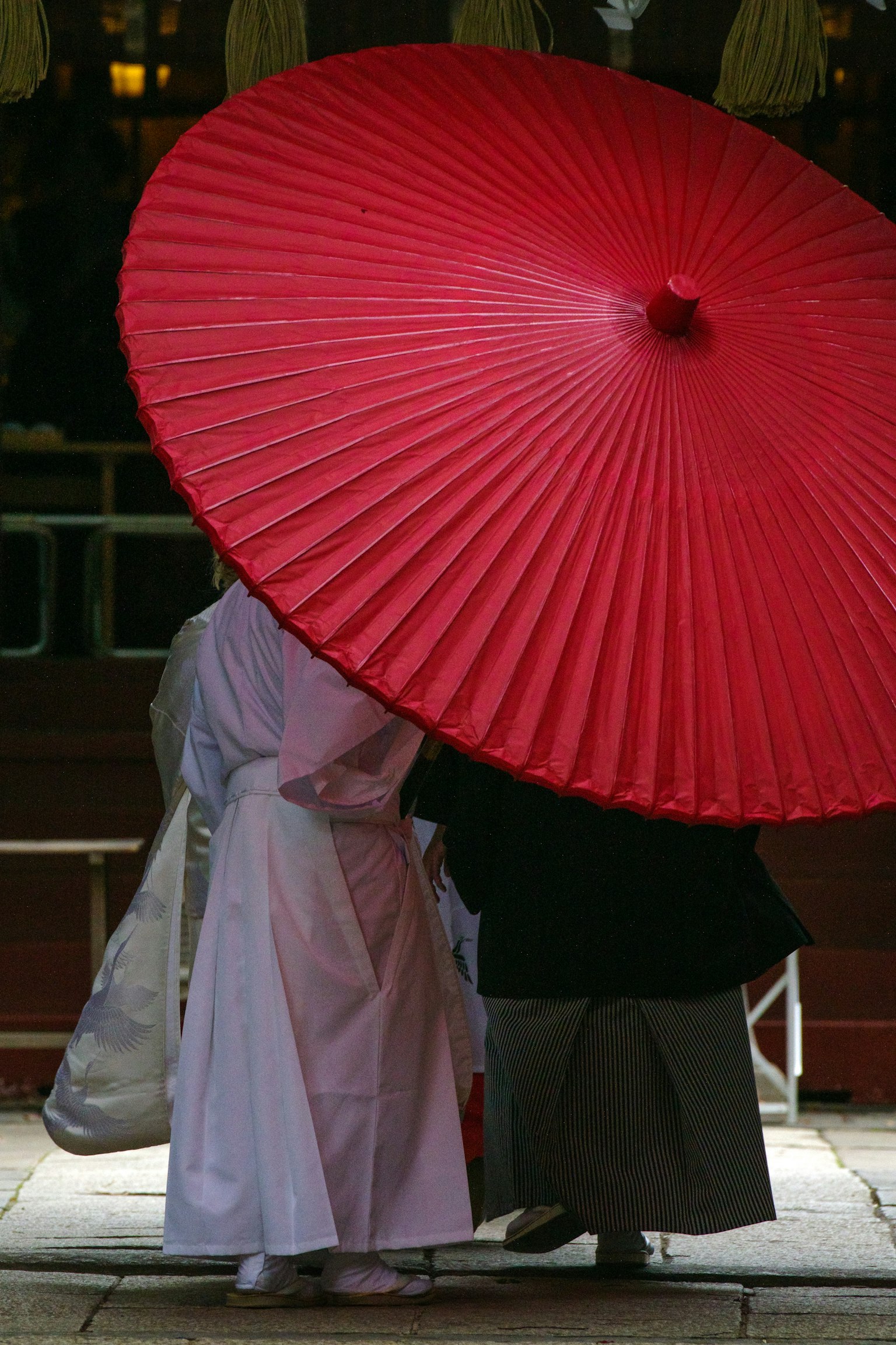 两个人在红伞下 一位穿白色服装的女性和一位男性