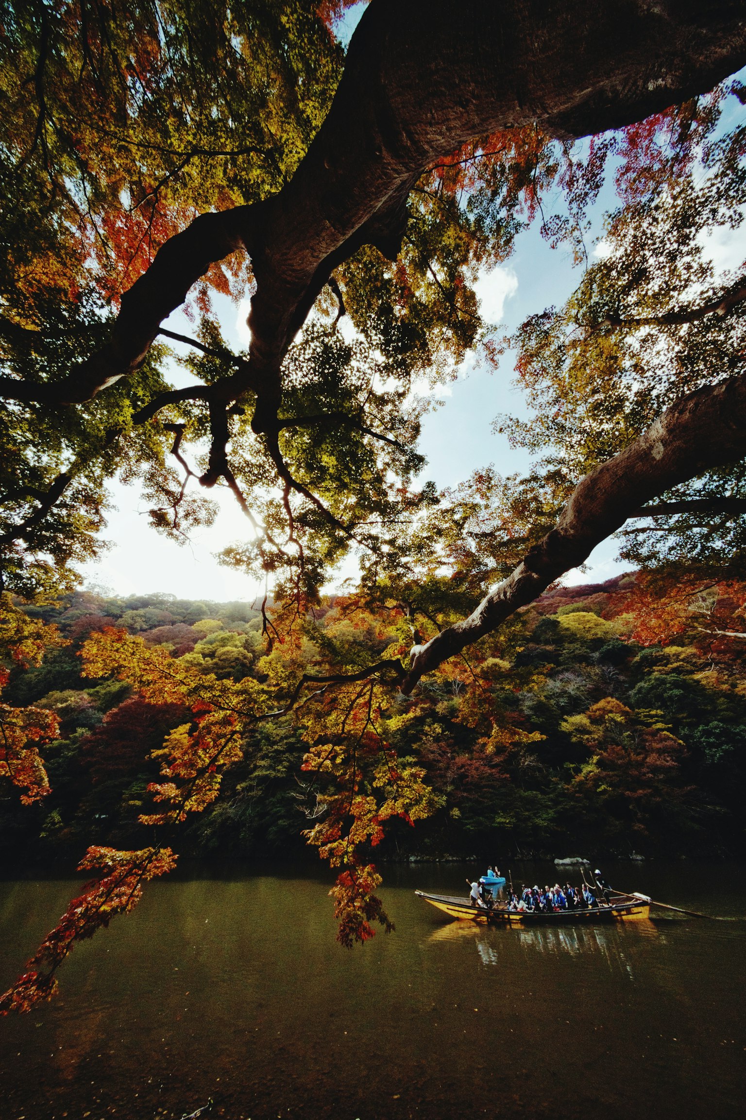 Des personnes dans un bateau sur une rivière tranquille entourée de feuillage d'automne