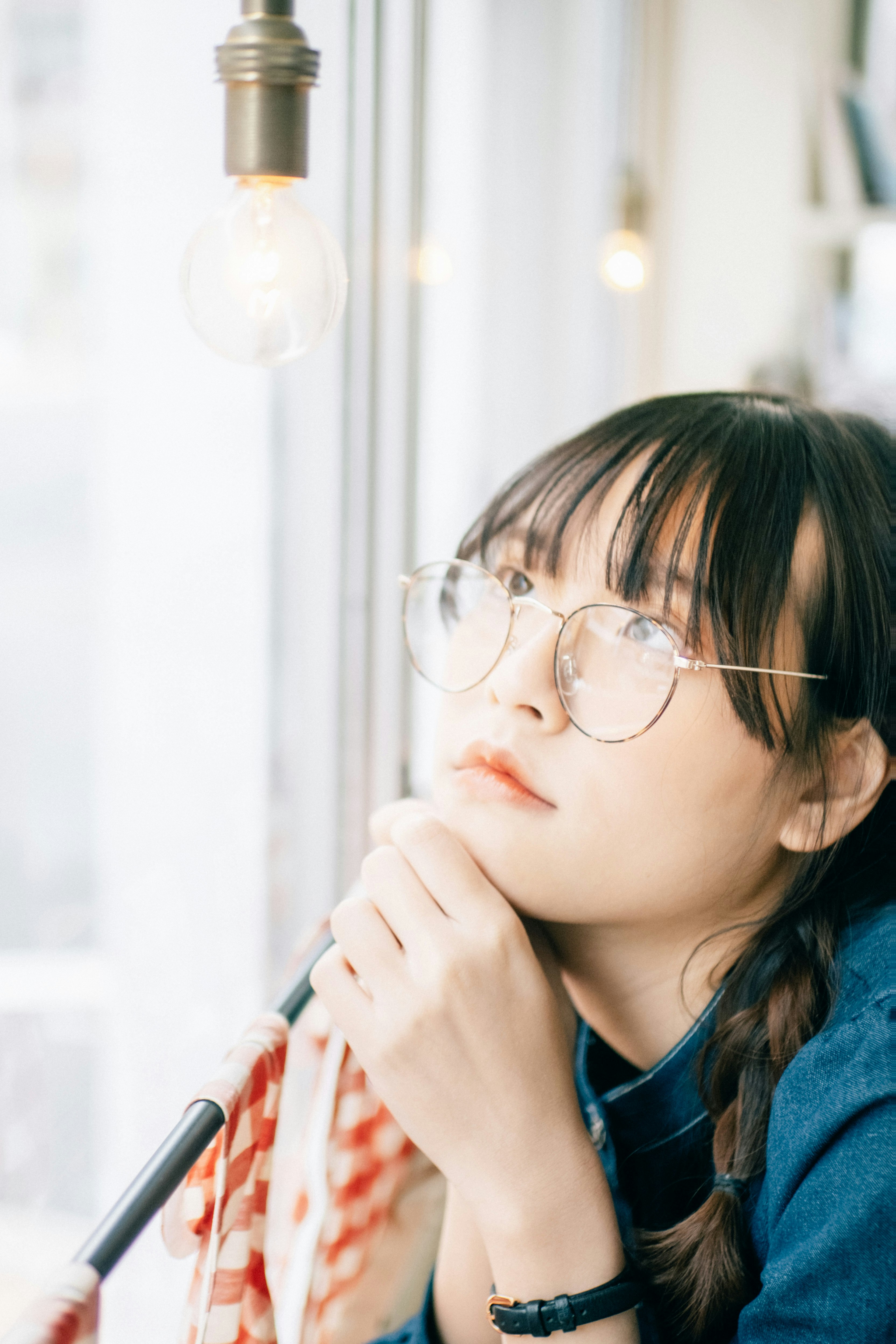 窗边戴眼镜的女性侧脸手持钢笔