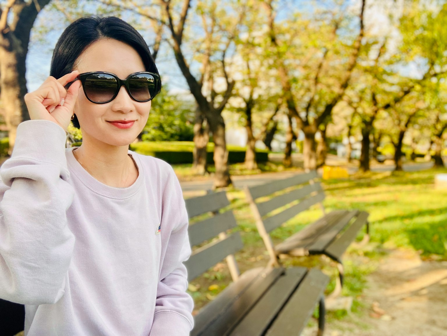 Một người phụ nữ đeo kính râm cười trong công viên