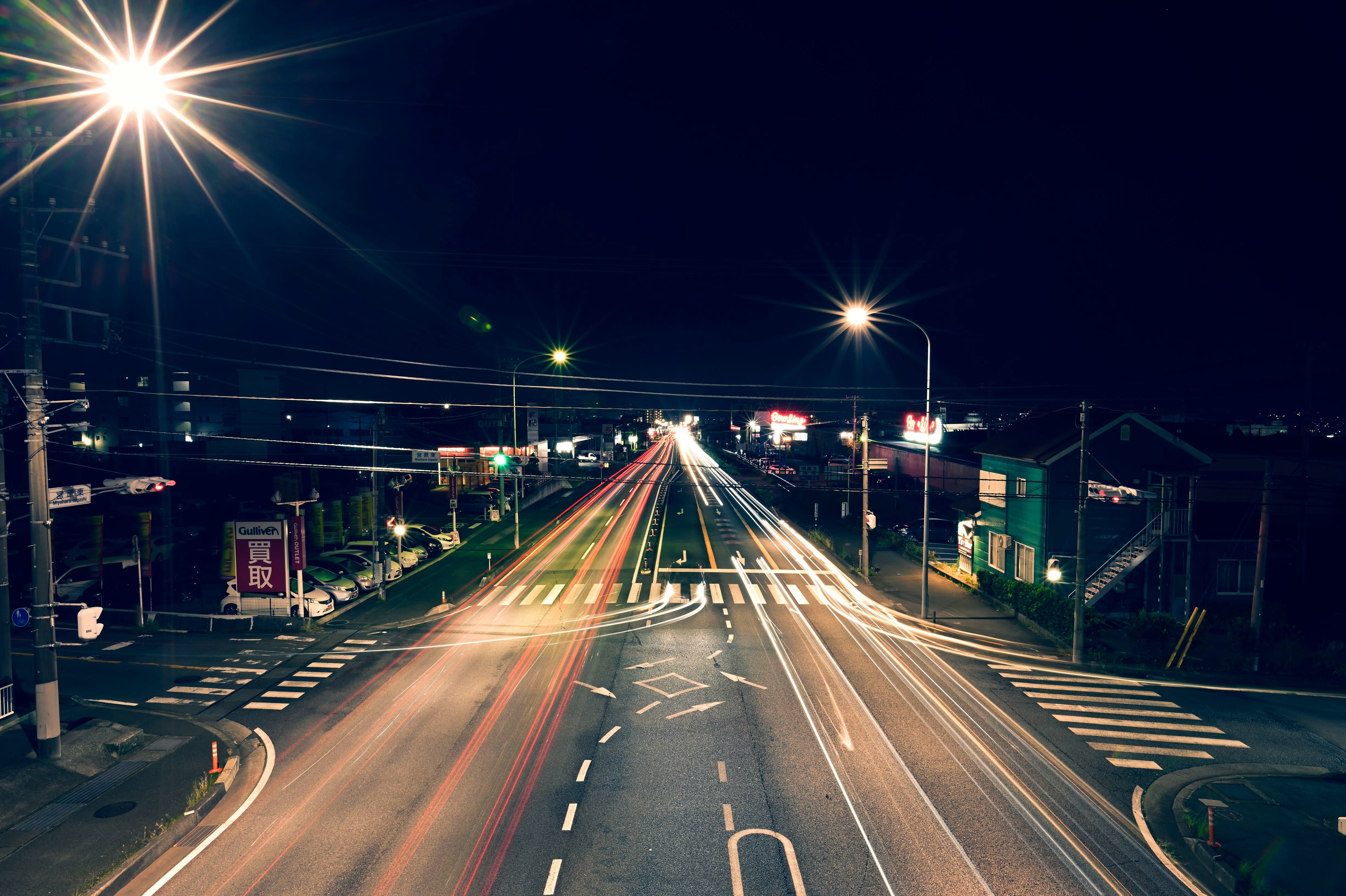 incrocio notturno con scie luminose lunghe su una strada rettilinea