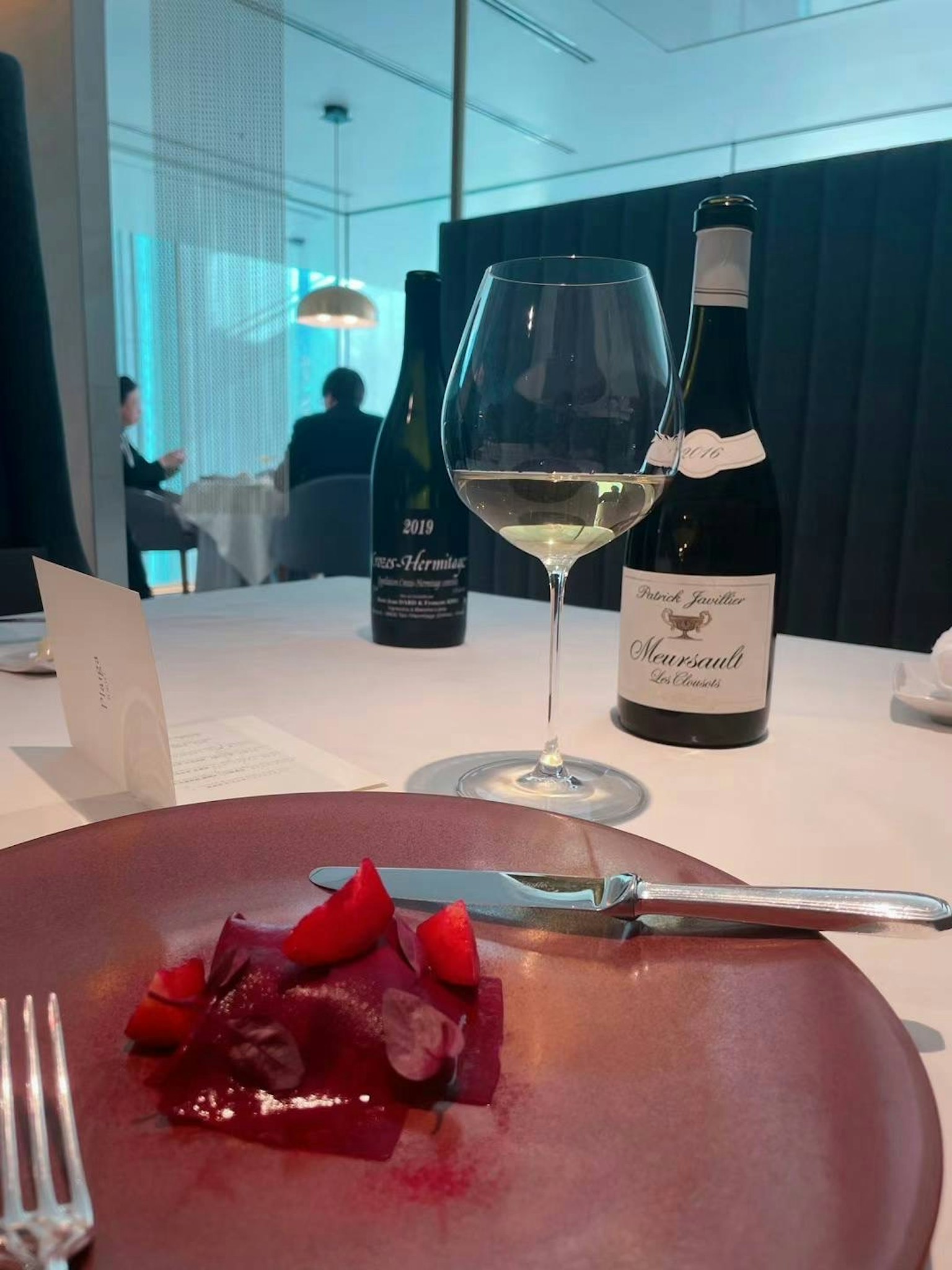 A beautifully arranged table with a dish and white wine