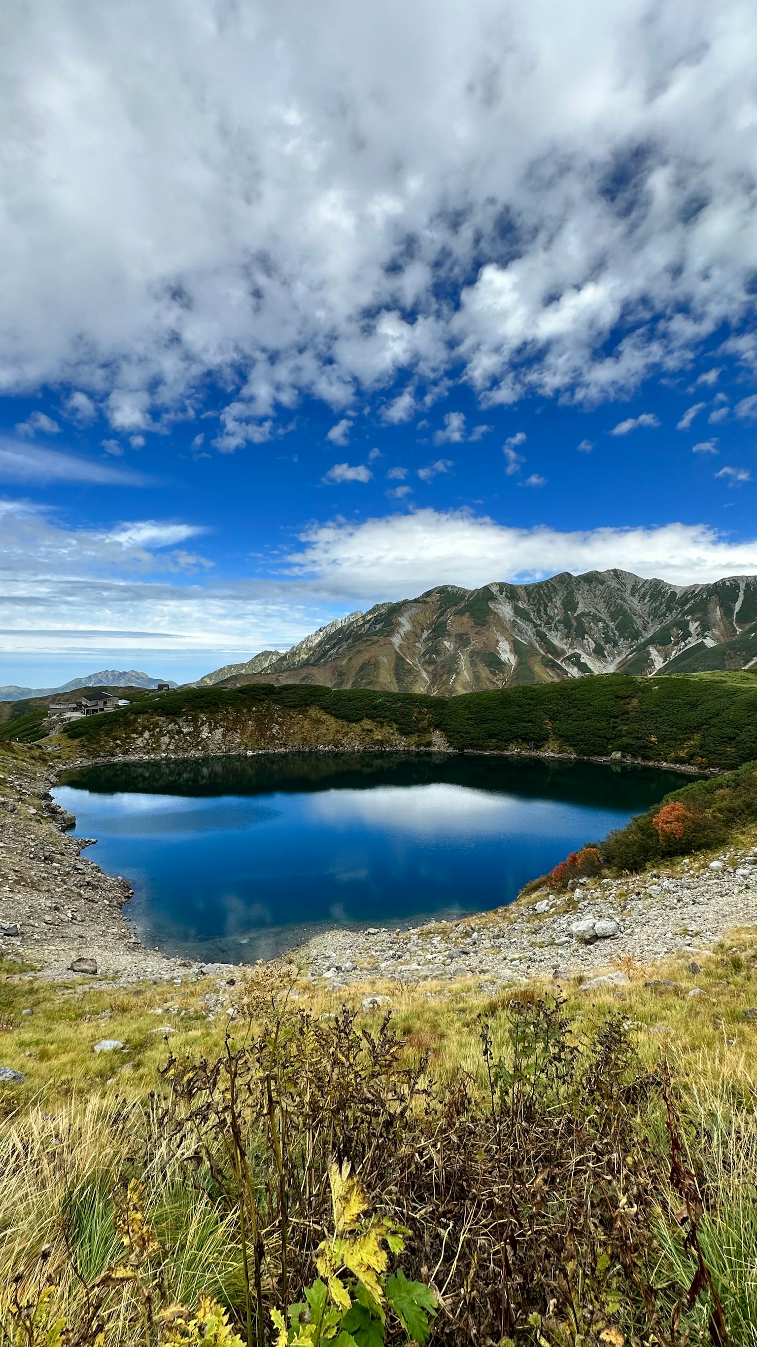 Vista escénica de un lago azul rodeado de montañas y nubes