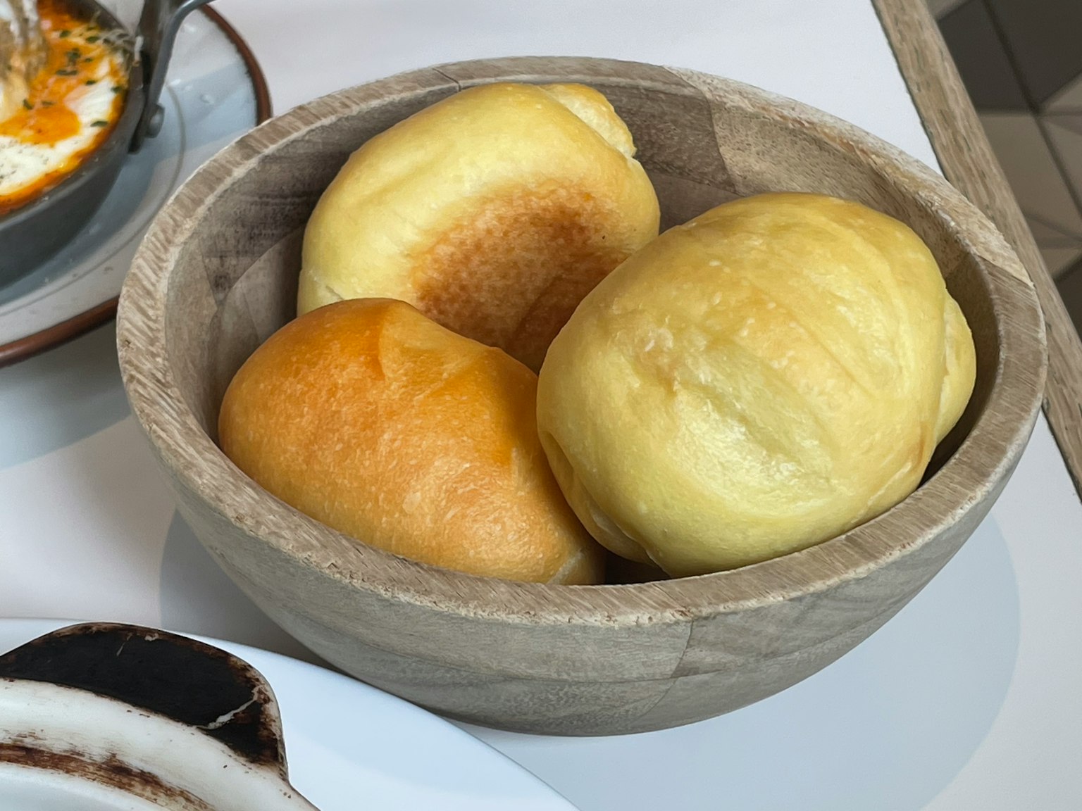 Three bread rolls in a wooden bowl