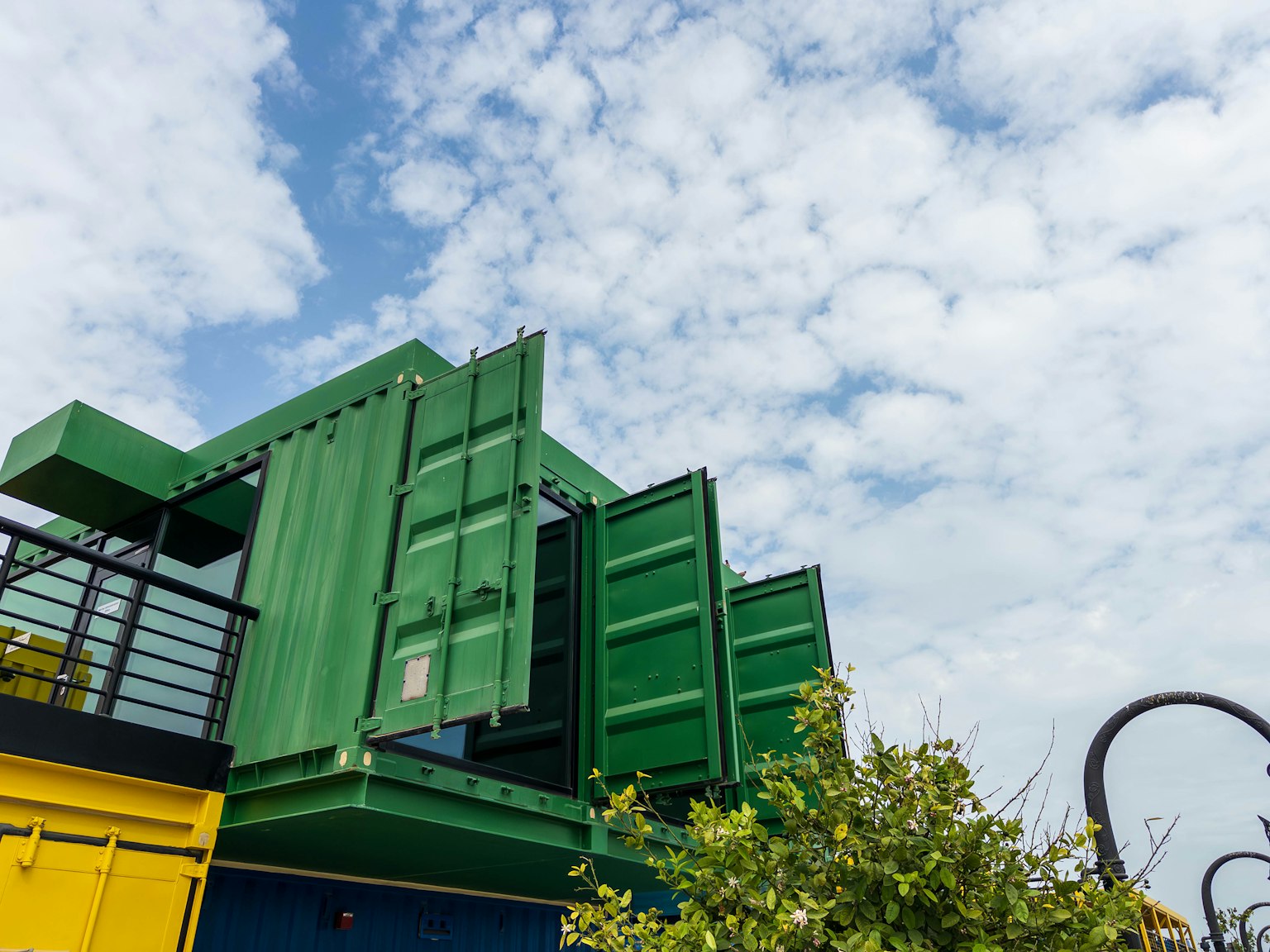 Maison en conteneurs verts avec des portes ouvertes sous un ciel bleu