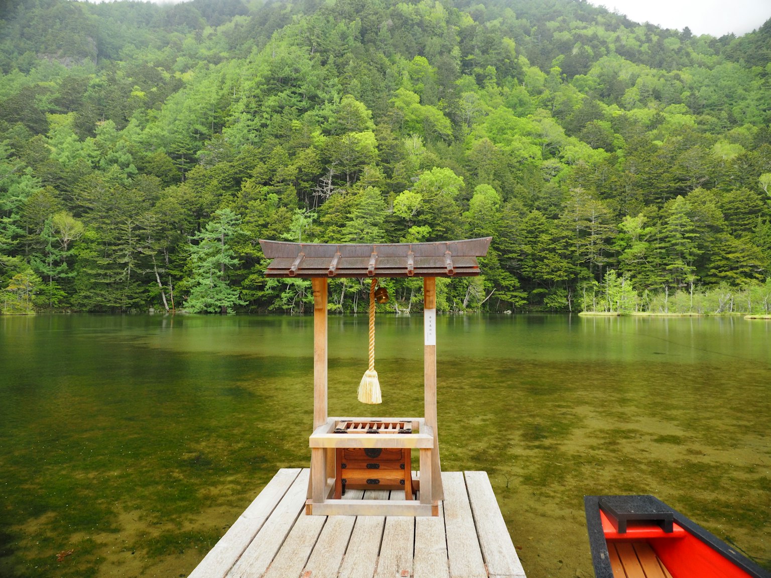 Struktur kecil di atas danau dengan pegunungan hijau subur di latar belakang