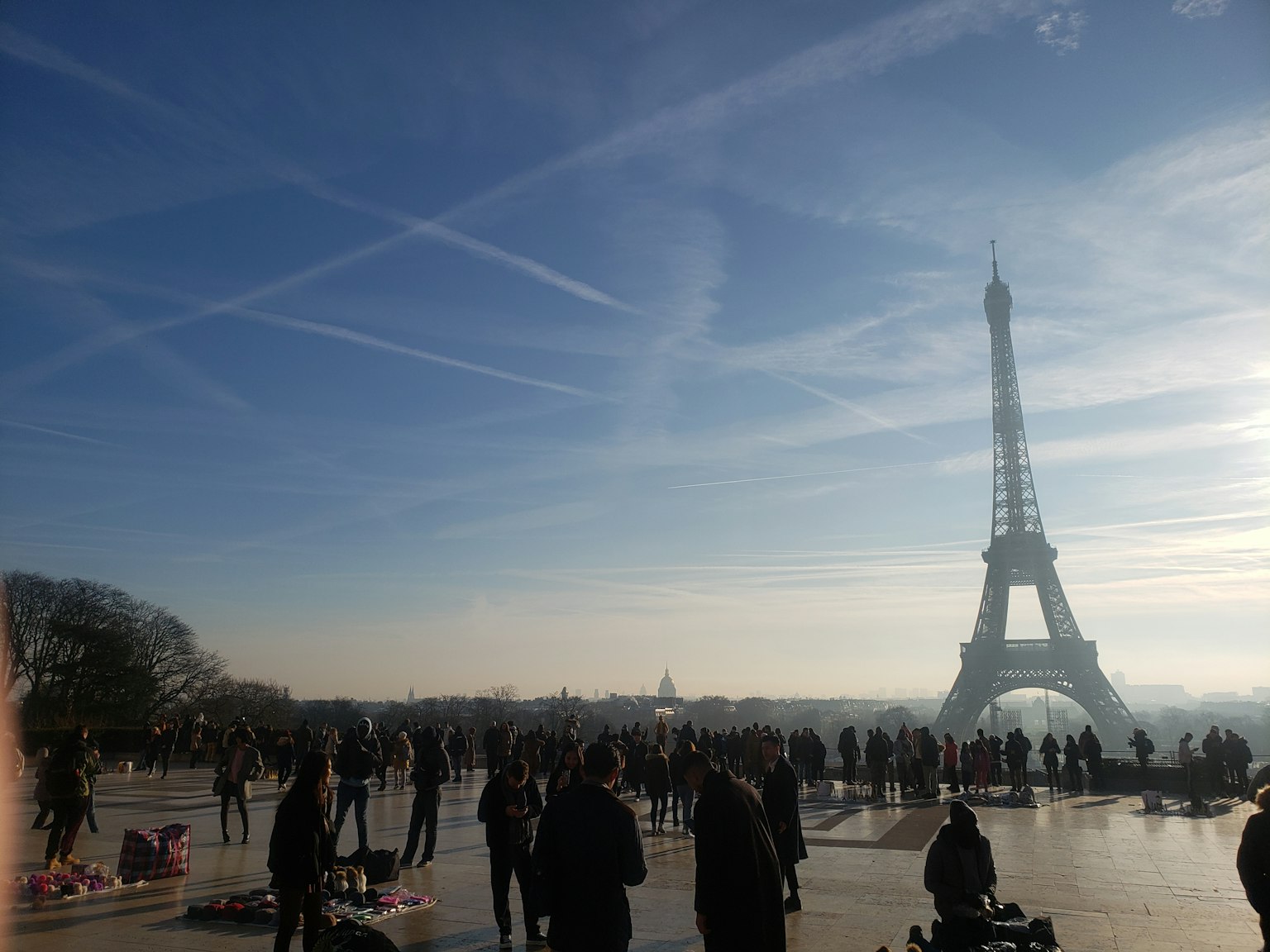 Wisatawan berkumpul di plaza dengan Menara Eiffel di latar belakang
