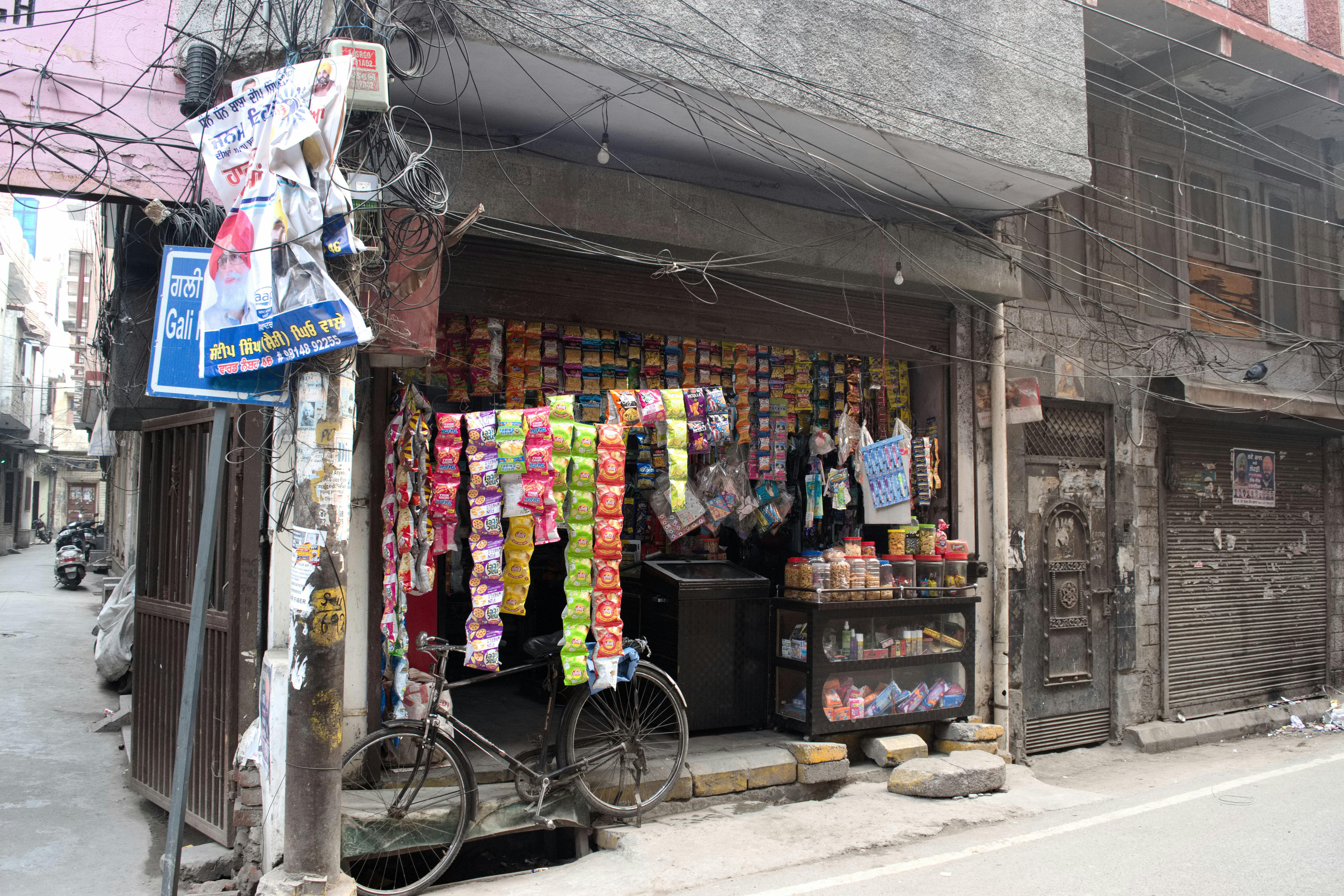 หน้าร้านเล็กๆ ในตรอกแคบ มีถุงขนมและจักรยานจอดอยู่