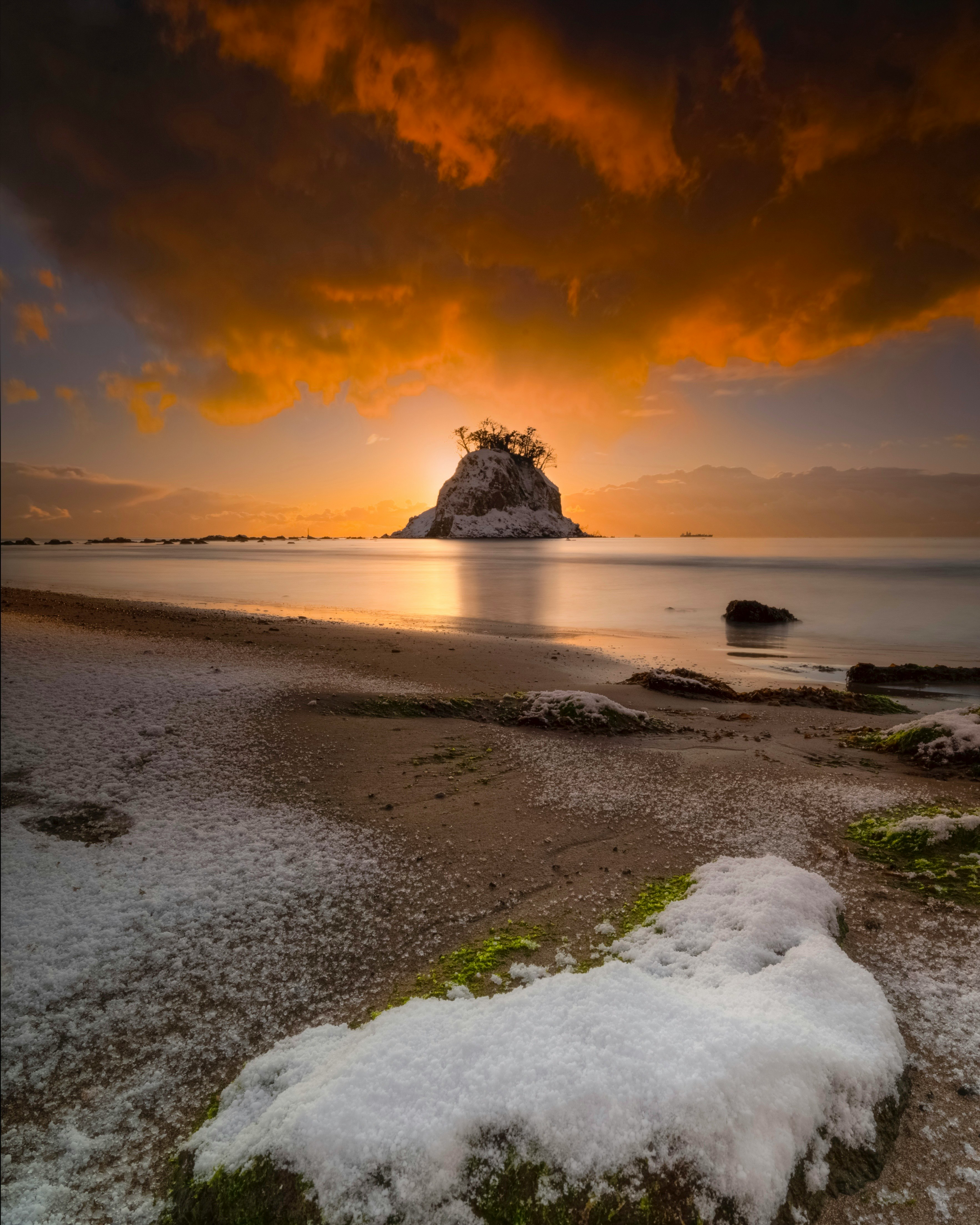 plage d’hiver au coucher du soleil avec vagues sur le sable et rocher