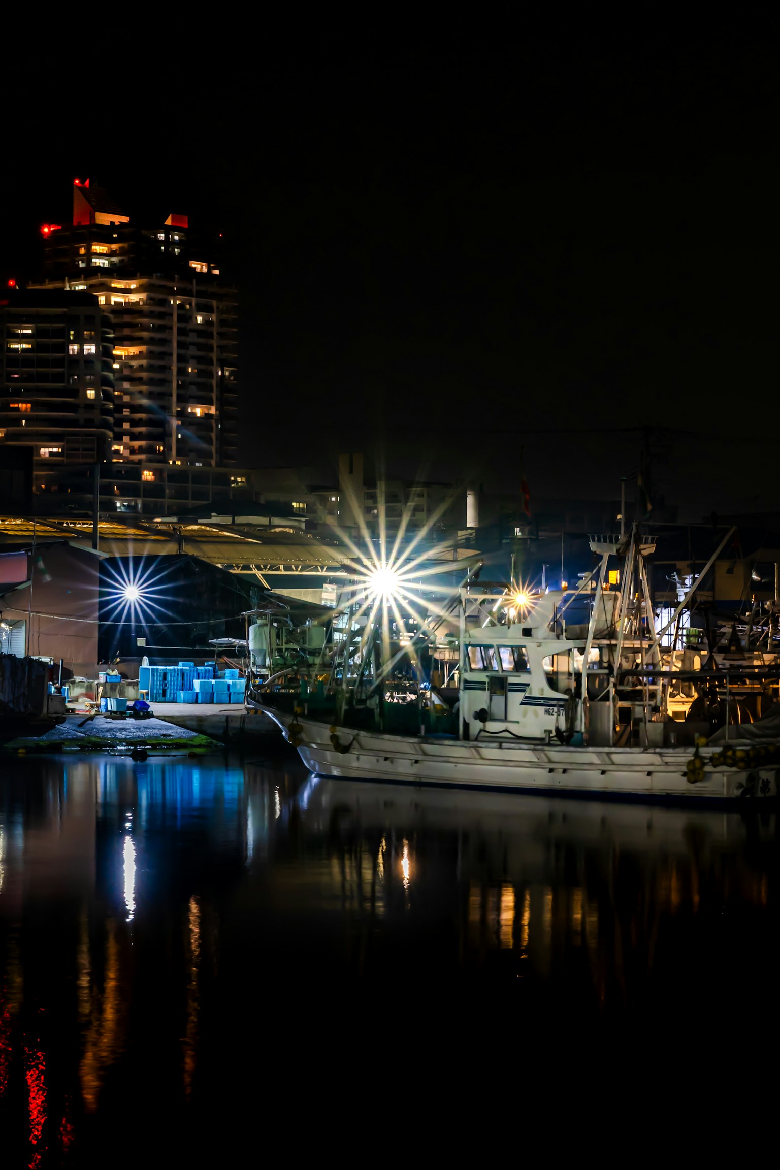 Una nave illuminata di notte vicino a un profilo urbano che si riflette nell'acqua