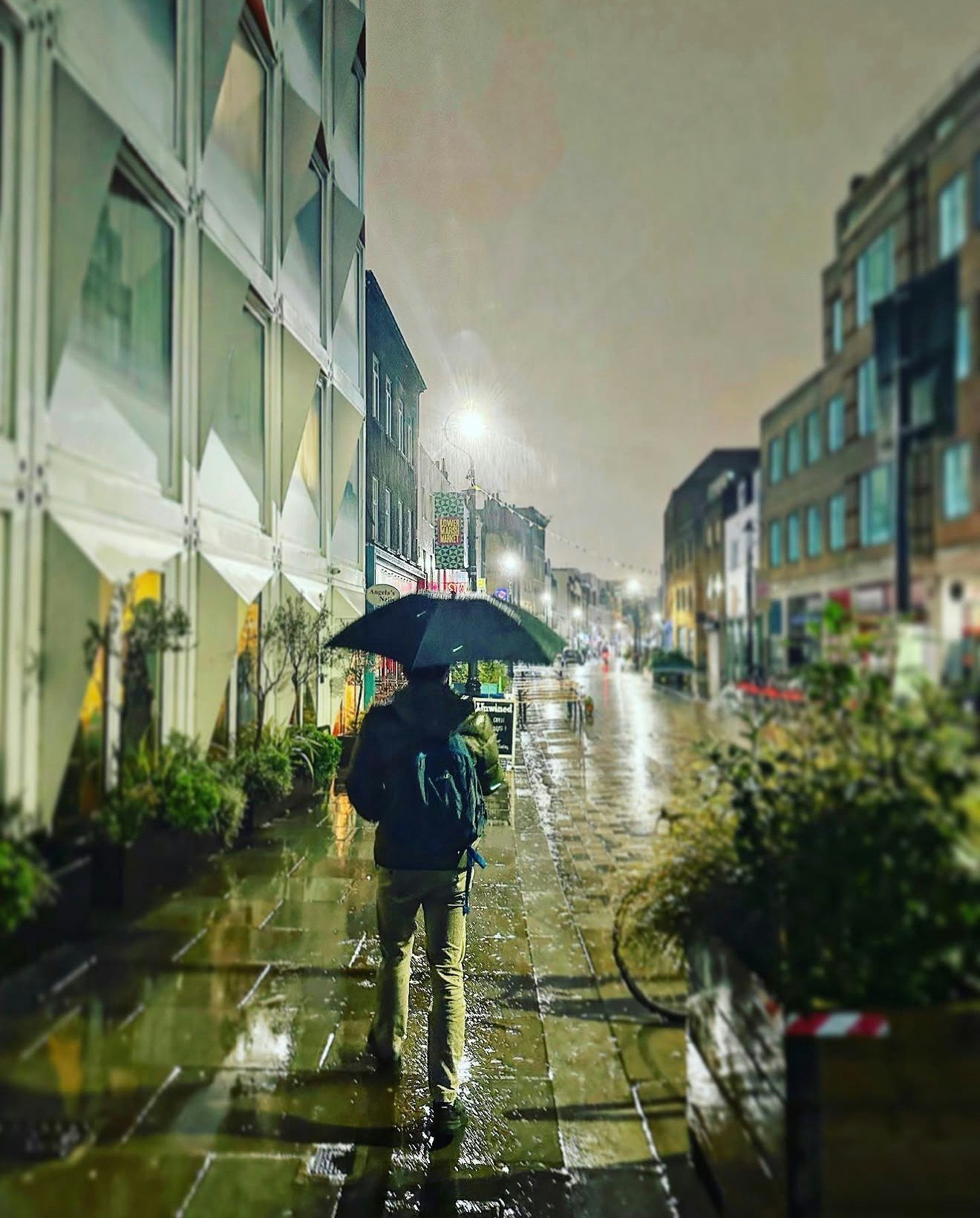 雨の路地で傘をさす人と濡れた街並み