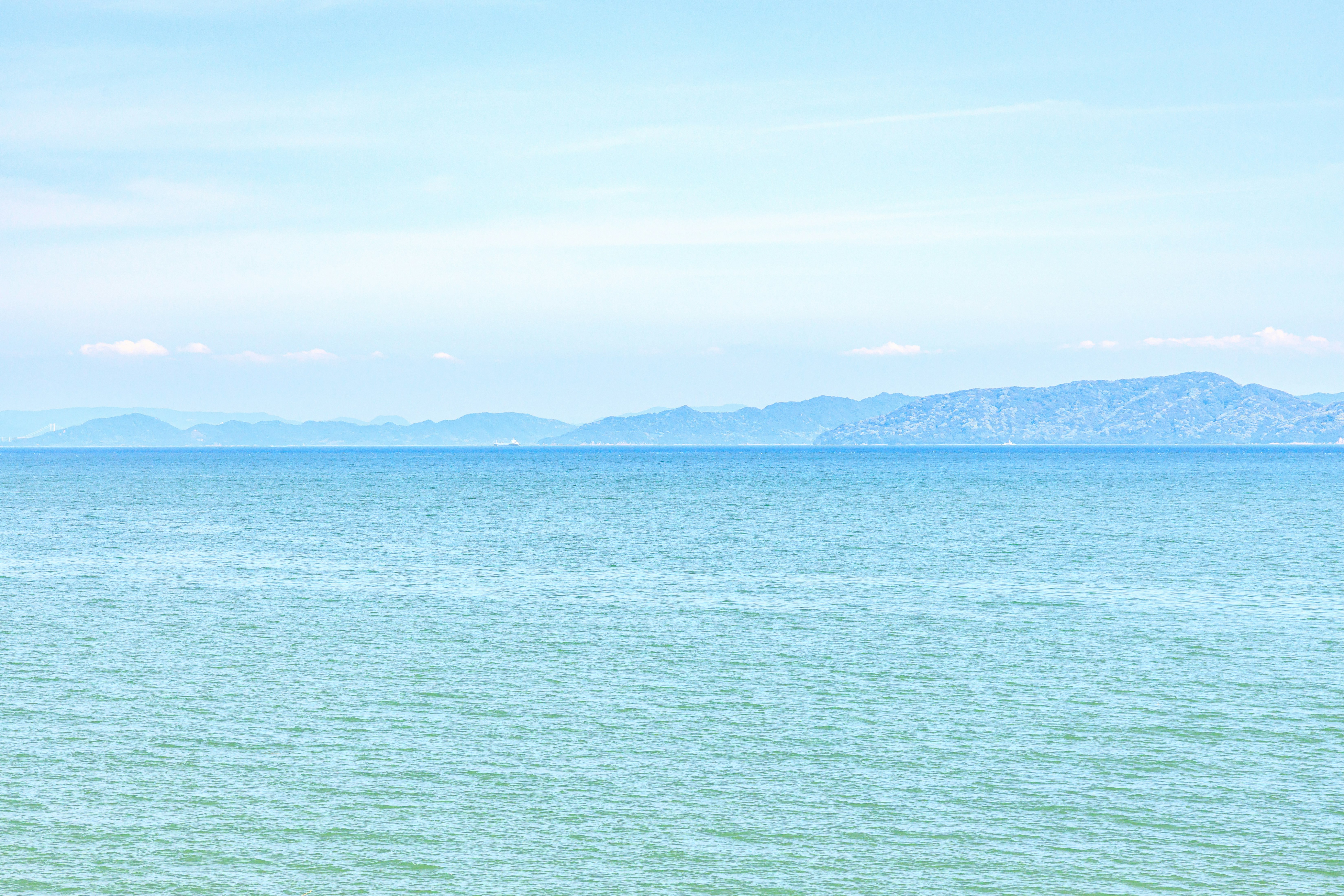 Ocean and distant mountain range under a blue sky