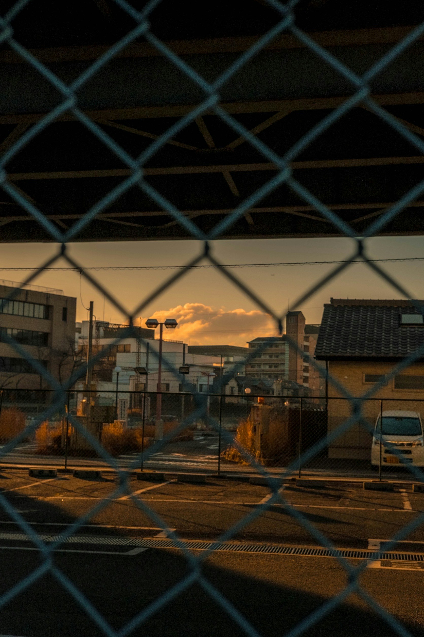 夕焼けの工業地帯をフェンス越しに望む景色