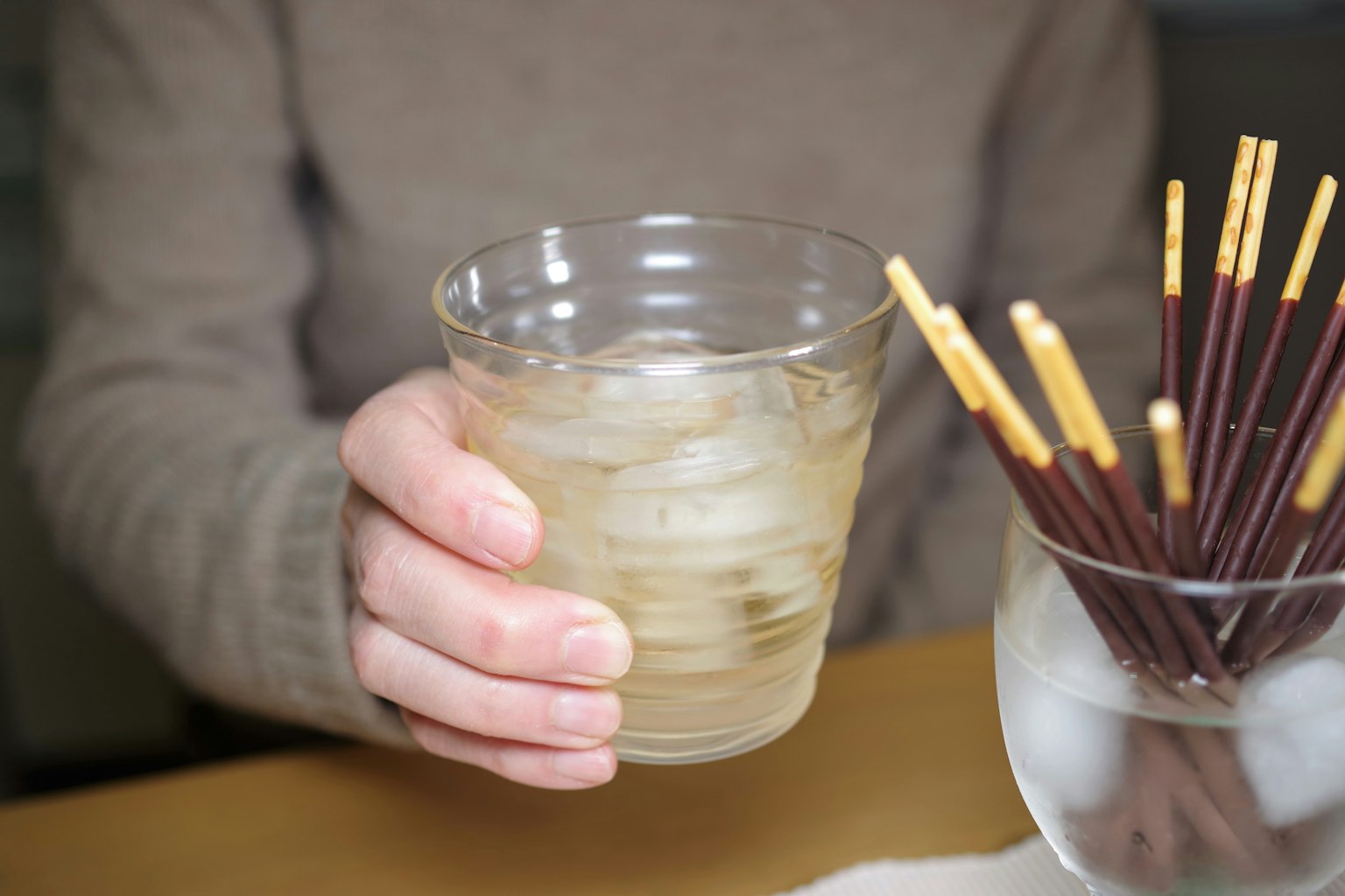 手握著裝有冰飲的杯子和零食棒