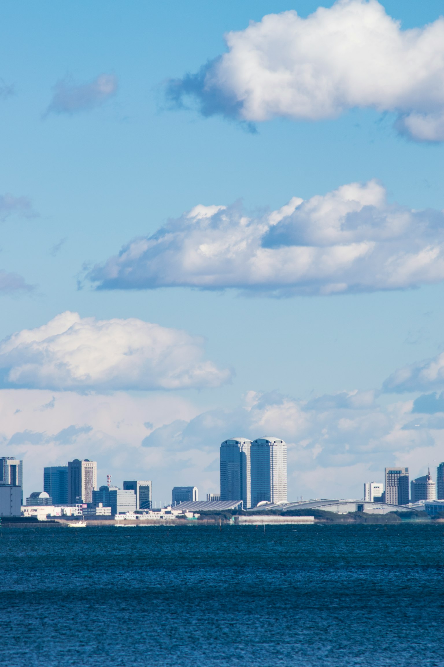 Skyline di città con cielo blu e nuvole bianche sopra l'acqua