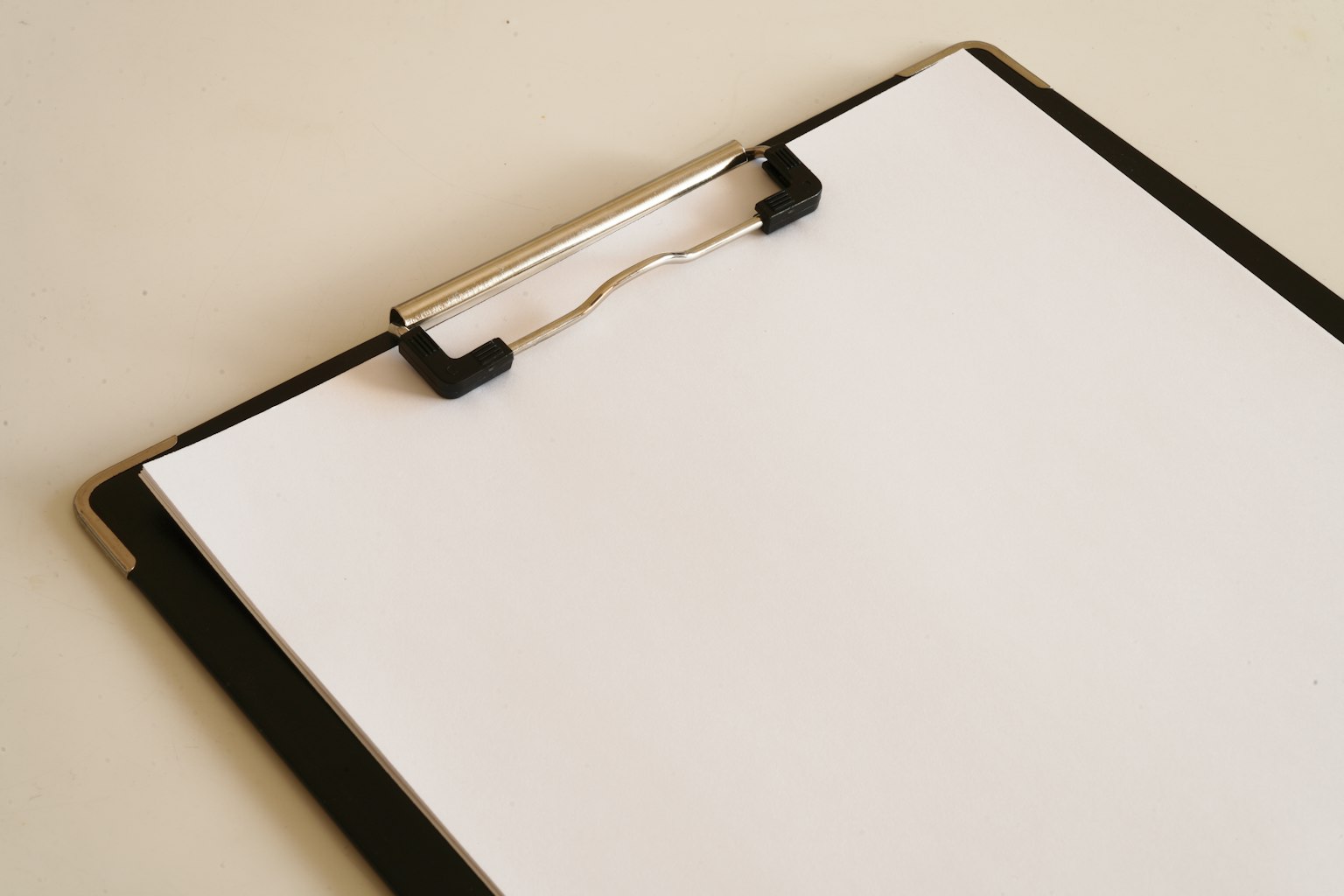 Tampilan atas clipboard hitam dengan selembar kertas putih kosong