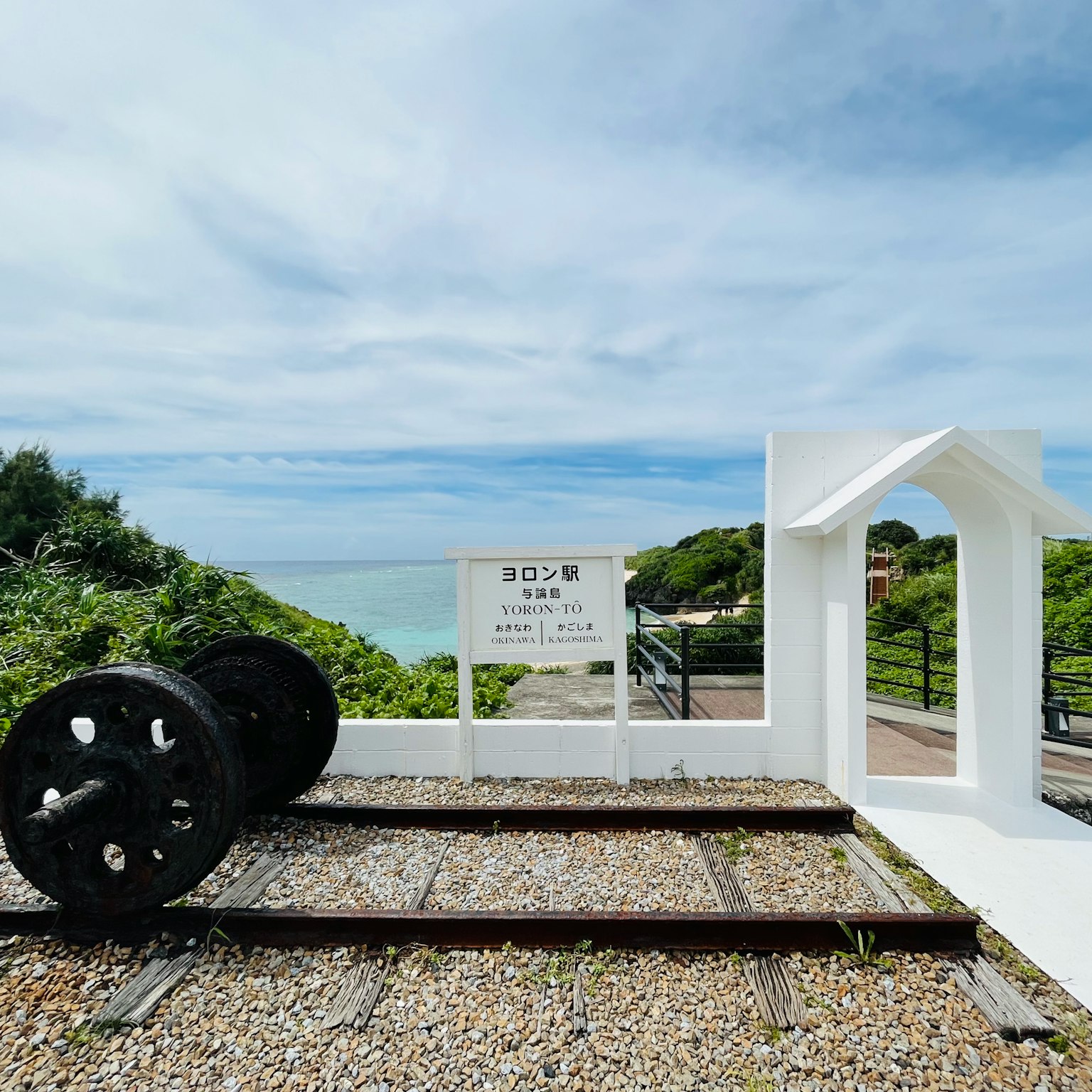 White structure with black wheels on railway tracks by the sea