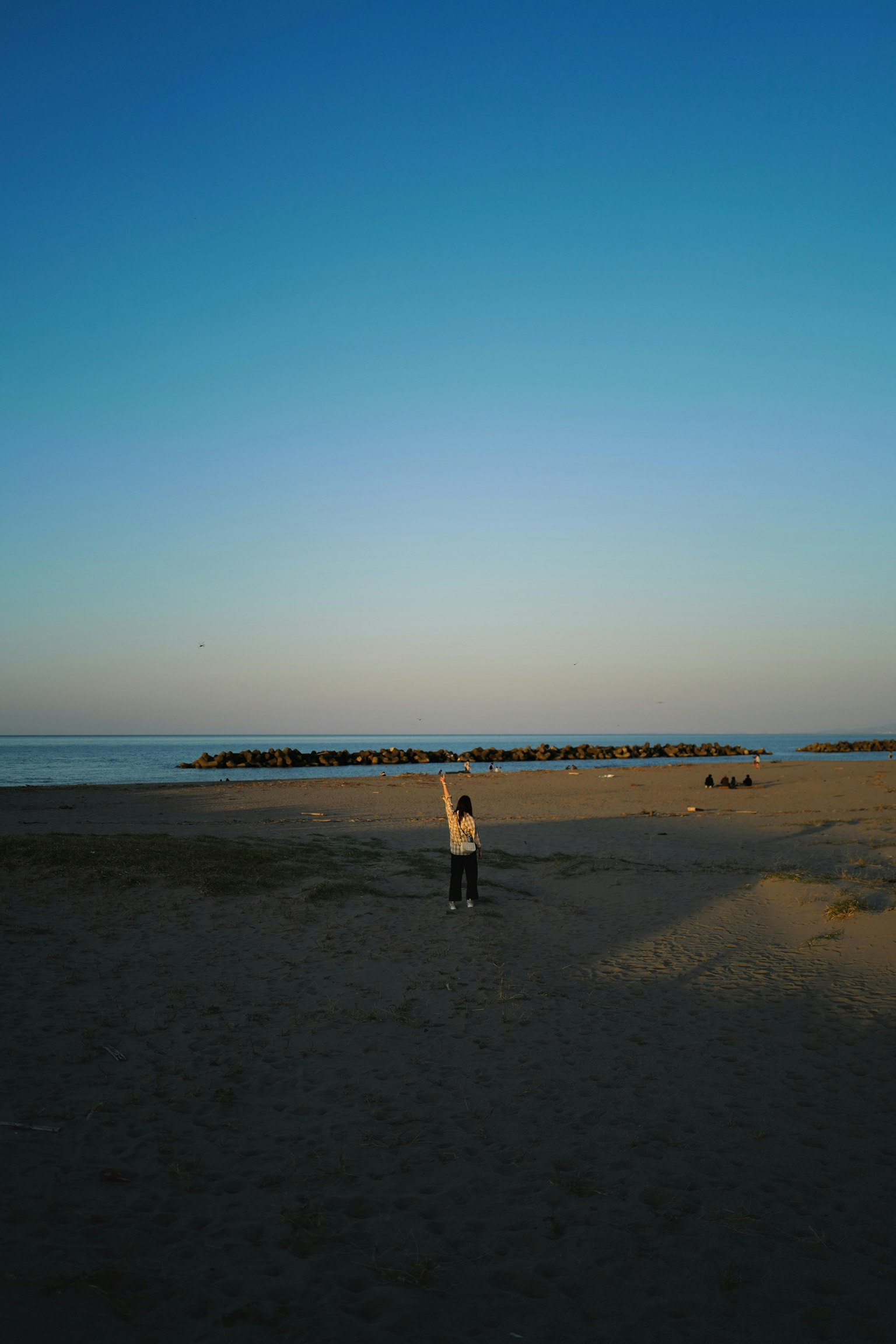 Silhouette di una persona in piedi contro un cielo blu e il mare