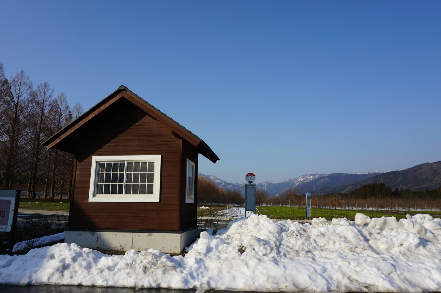 雪に覆われた風景に立つ小さな茶色の小屋と青空