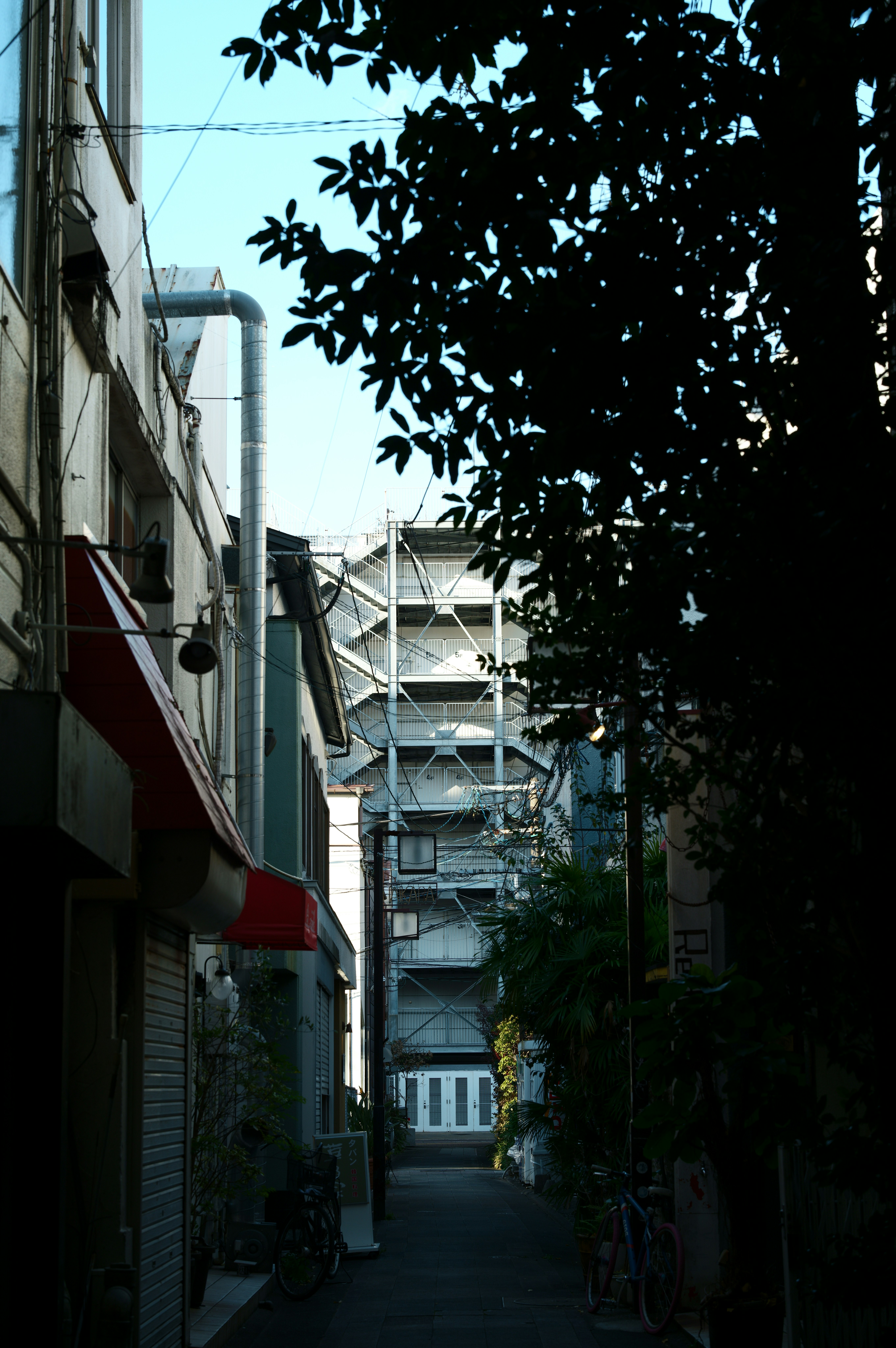 路地の奥に続く建物と自転車のある風景