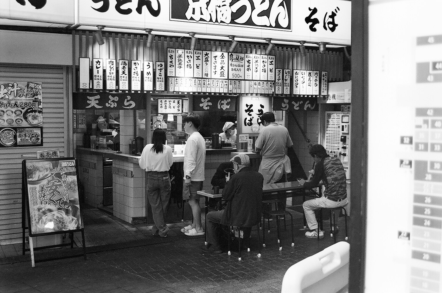 Immagine in bianco e nero di un ristorante di udon con clienti che mangiano
