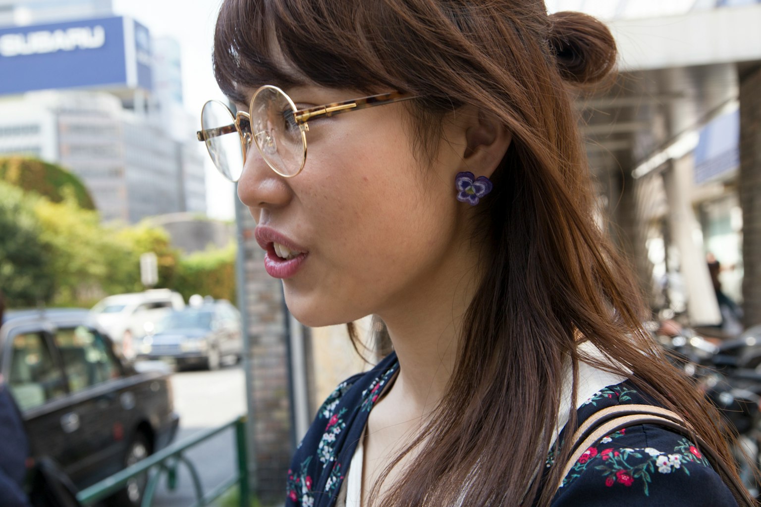 Femme avec des lunettes vue de profil portant des boucles d'oreilles violettes
