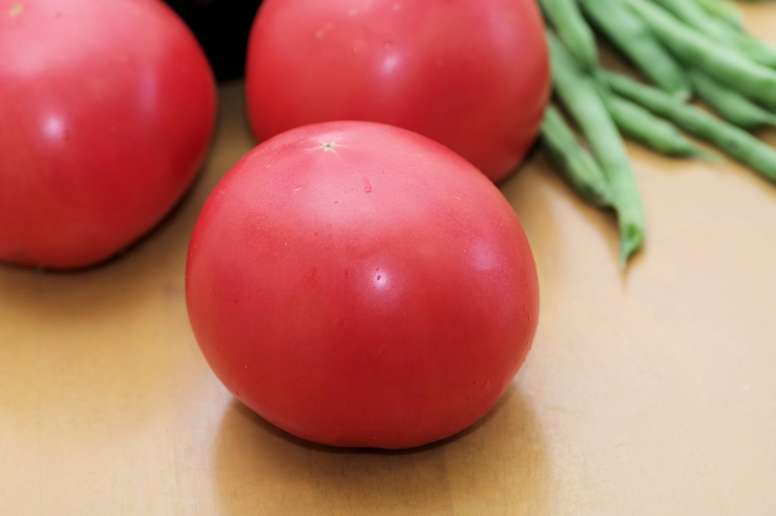 Tomates rojas y ejotes sobre una superficie de madera